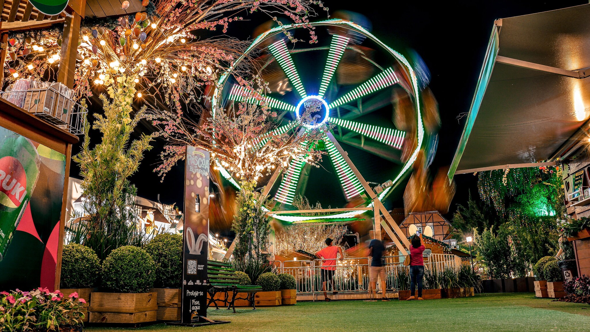 Auf einem Festplatz steht ein Riesenrad, das beleuchtet ist.