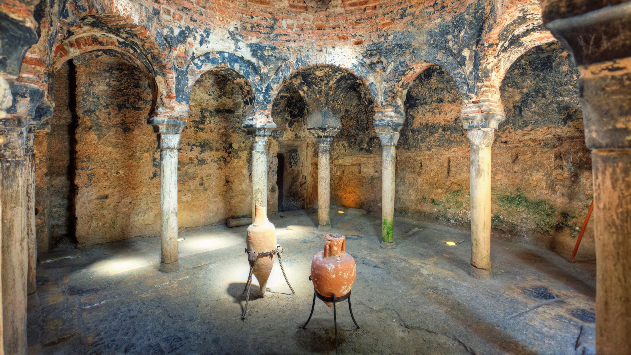 amex-magazin-geheimtipps-palma-amphoren Runde Ruinenstätte mit Säulenbögen und zwei aufgestellten Amphoren im Zentrum.