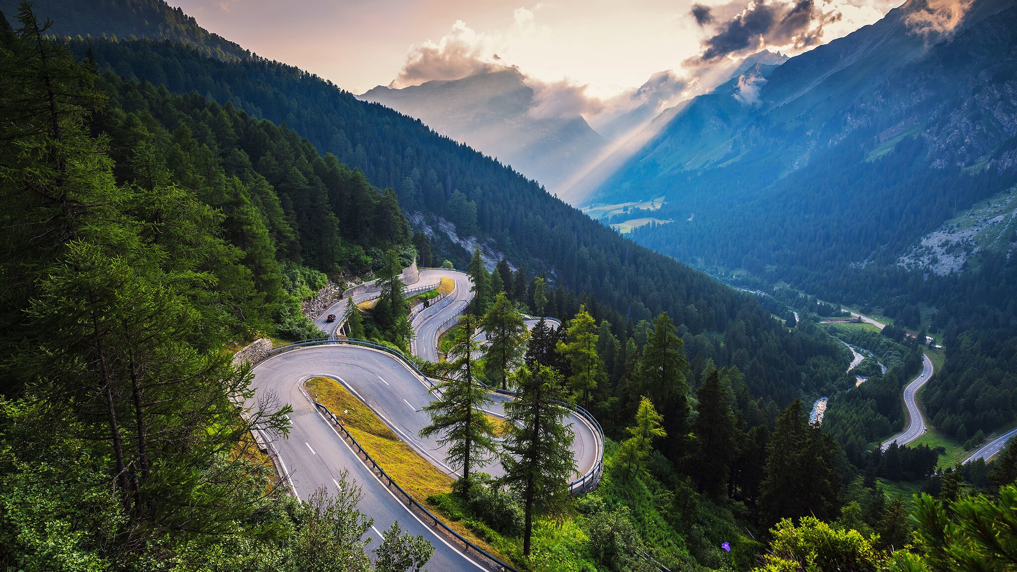 Eine kurvige Straße führt durch Berge und Wälder.