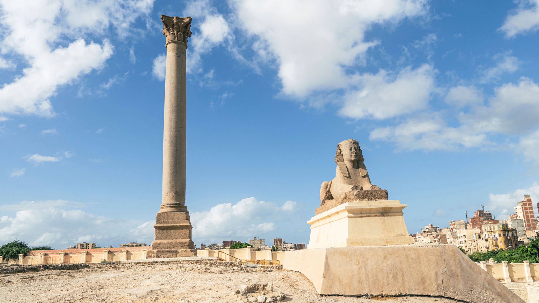 Tempelruine mit Säule und Sphinx unter freiem Himmel auf einem Hügel in einem Stadtgebiet. Tempelruine mit Säule und Sphinx unter freiem Himmel auf einem Hügel in einem Stadtgebiet.
