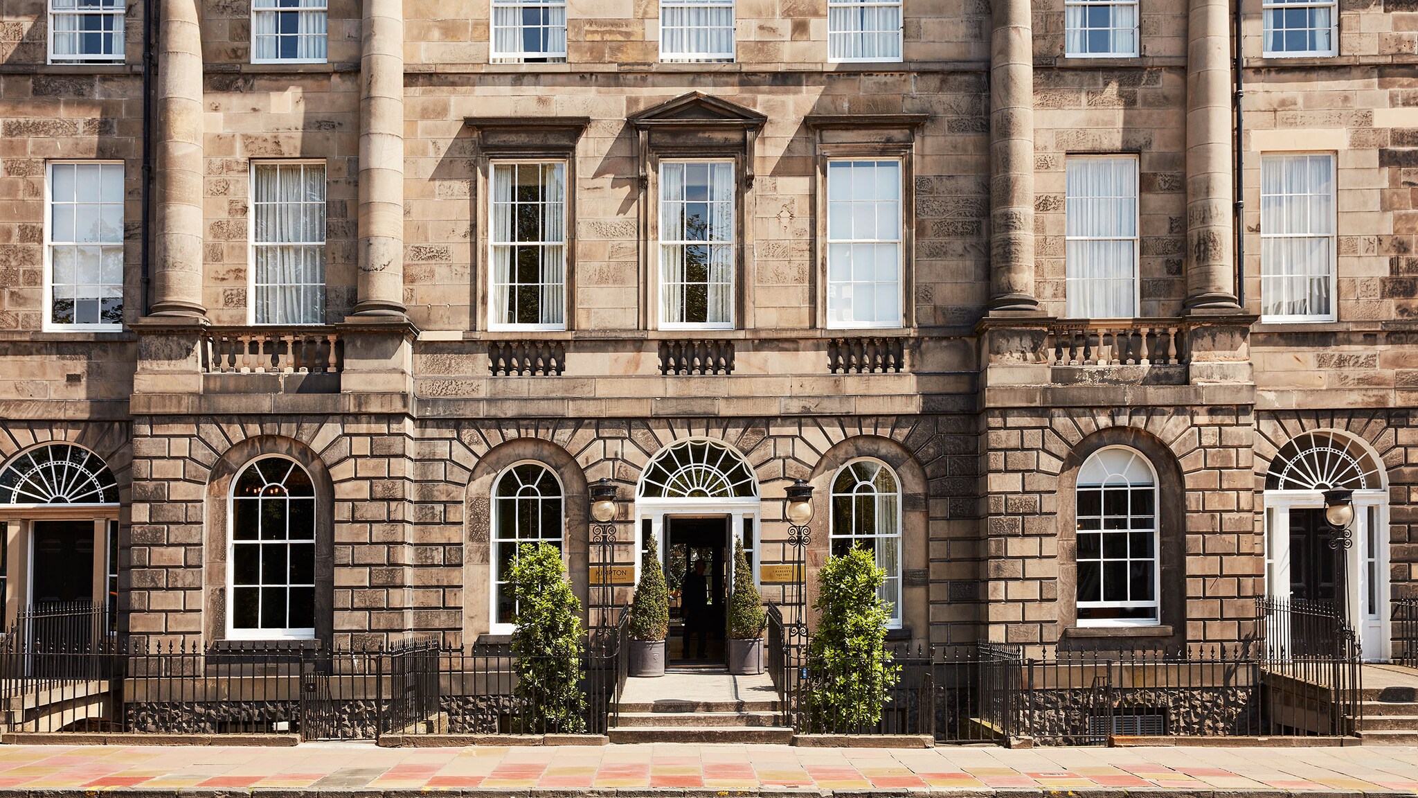 Georgianische Stadthausfassade mit Rundbogenfenstern um den Eingangsbereich zu einem Luxushotel.