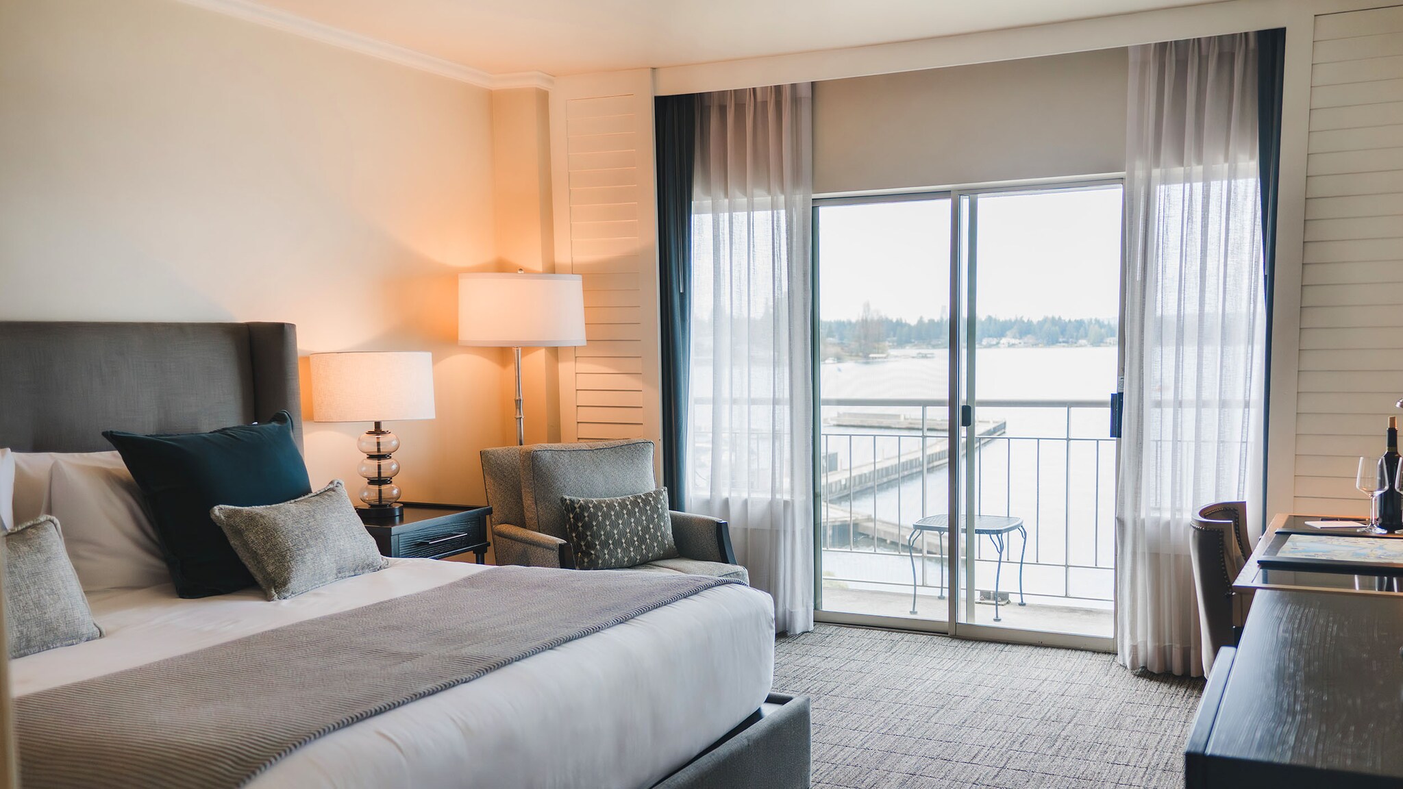In einem hellen Hotelzimmer steht ein Bett mit Nachttisch und Beleuchtung.