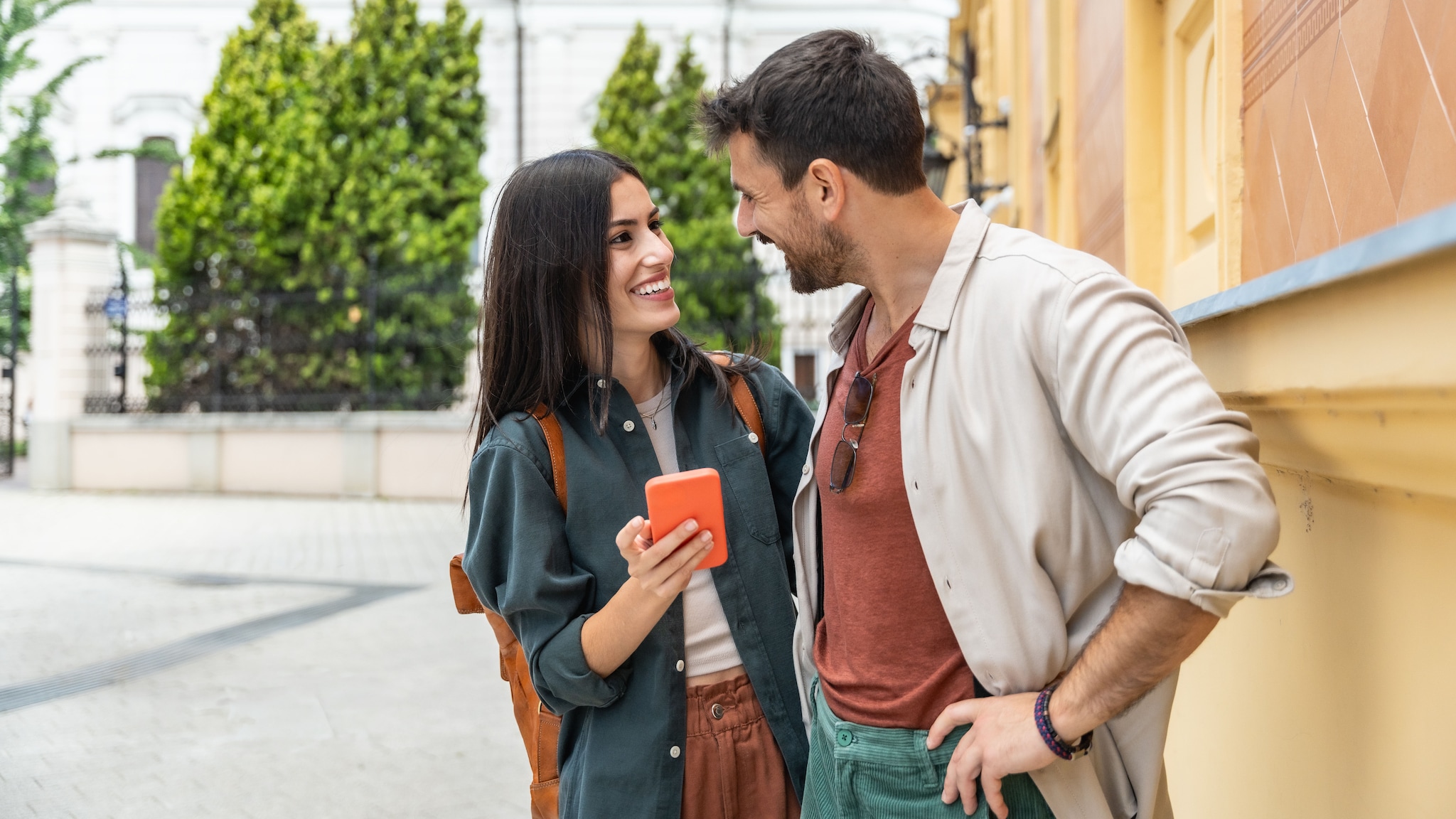 Ein Paar steht auf der Straße und schaut sich an, sie hält ein Smartphone in der Hand.
