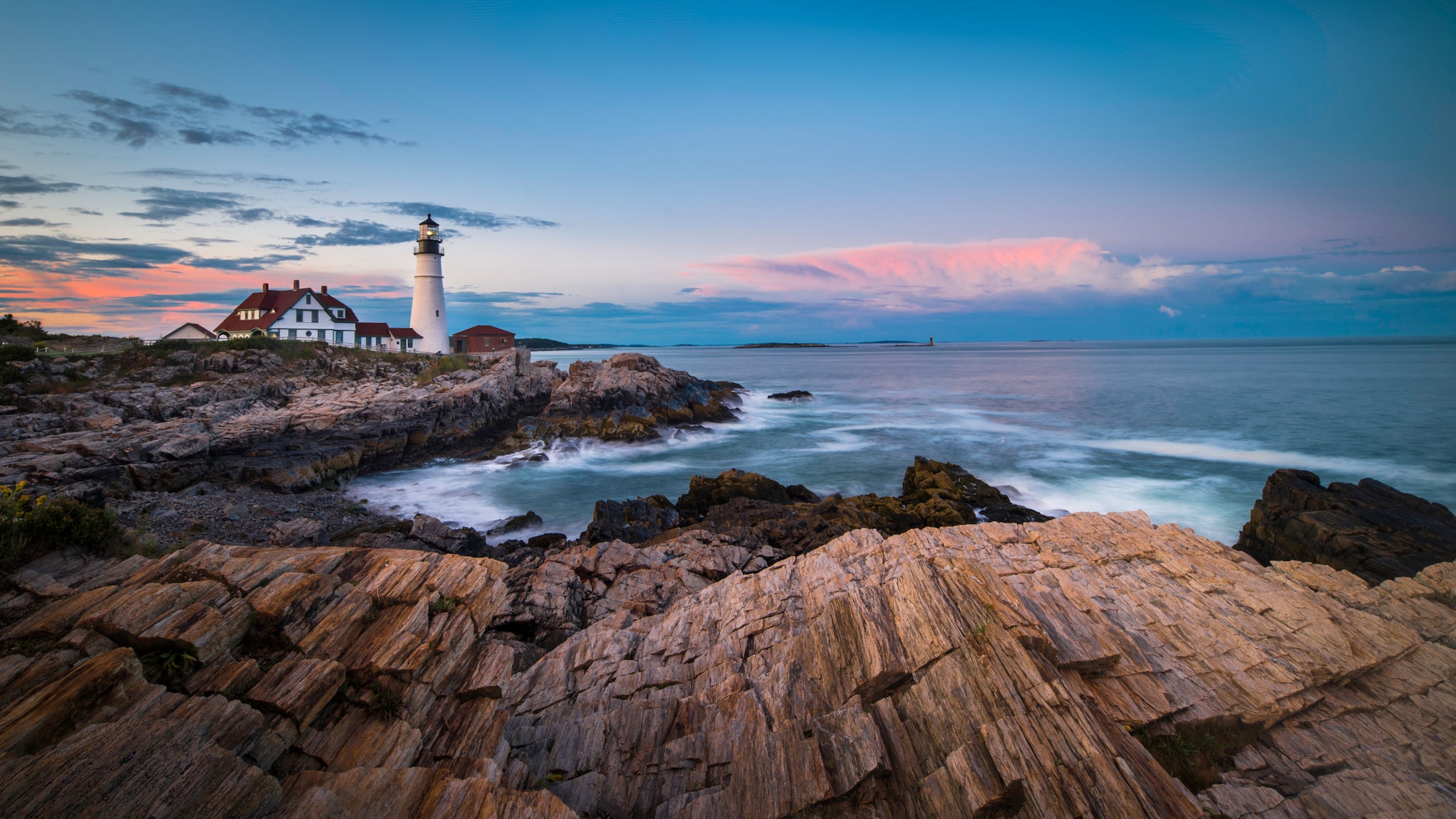 Leuchtturm und Haus an einer Bucht an einer schroffen Felsküste bei Abenddämmerung. Leuchtturm und Haus an einer Bucht an einer schroffen Felsküste bei Abenddämmerung.