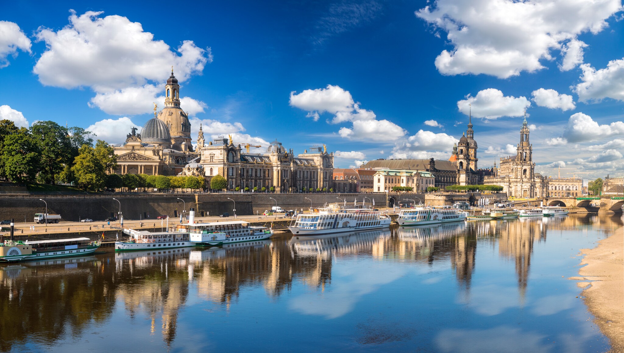Stadtpanorama von Dresden mit historischen Bauten am Fluss mit festgemachten Ausflugsbooten.