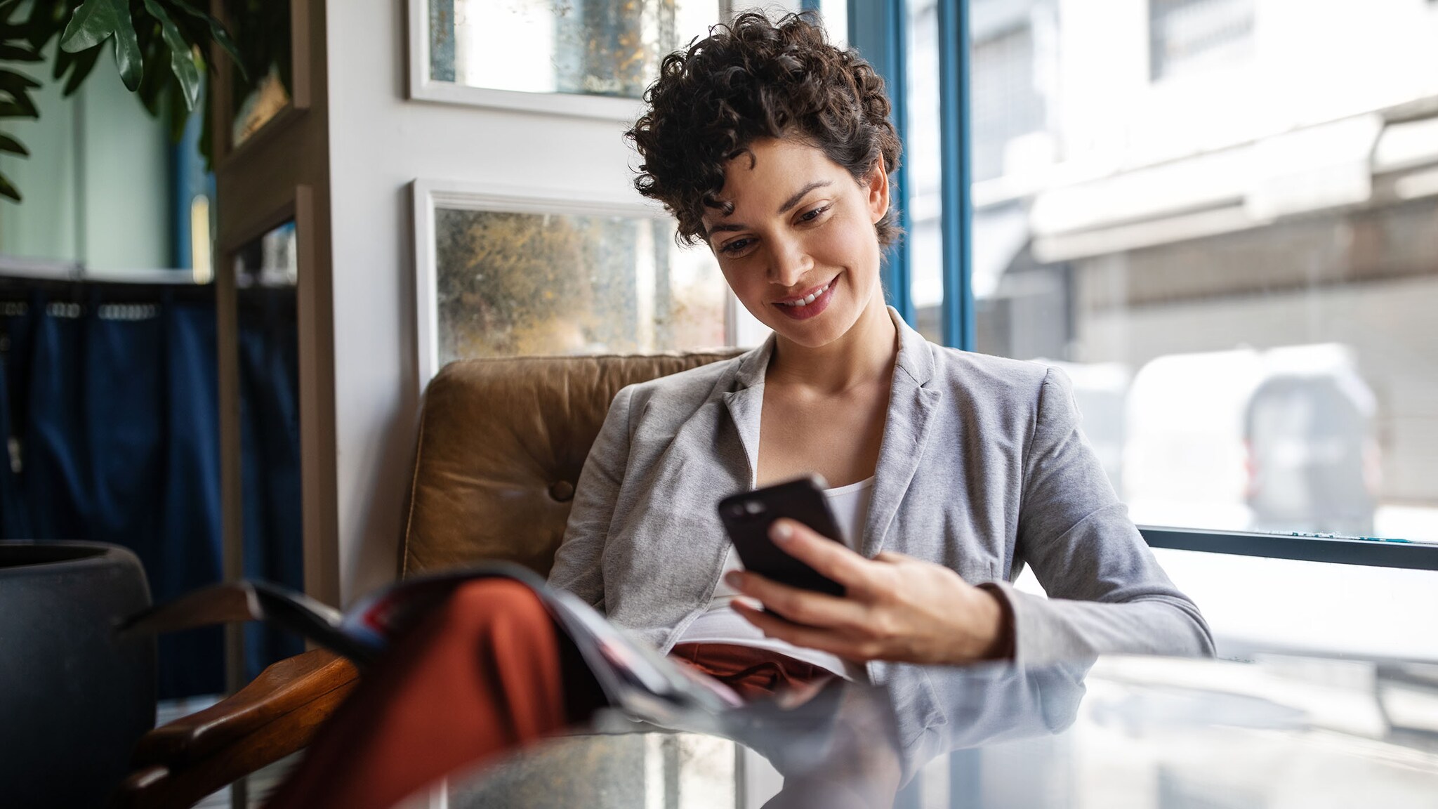 Eine Frau sitzt in einem Café und schaut auf ihr Smartphone.