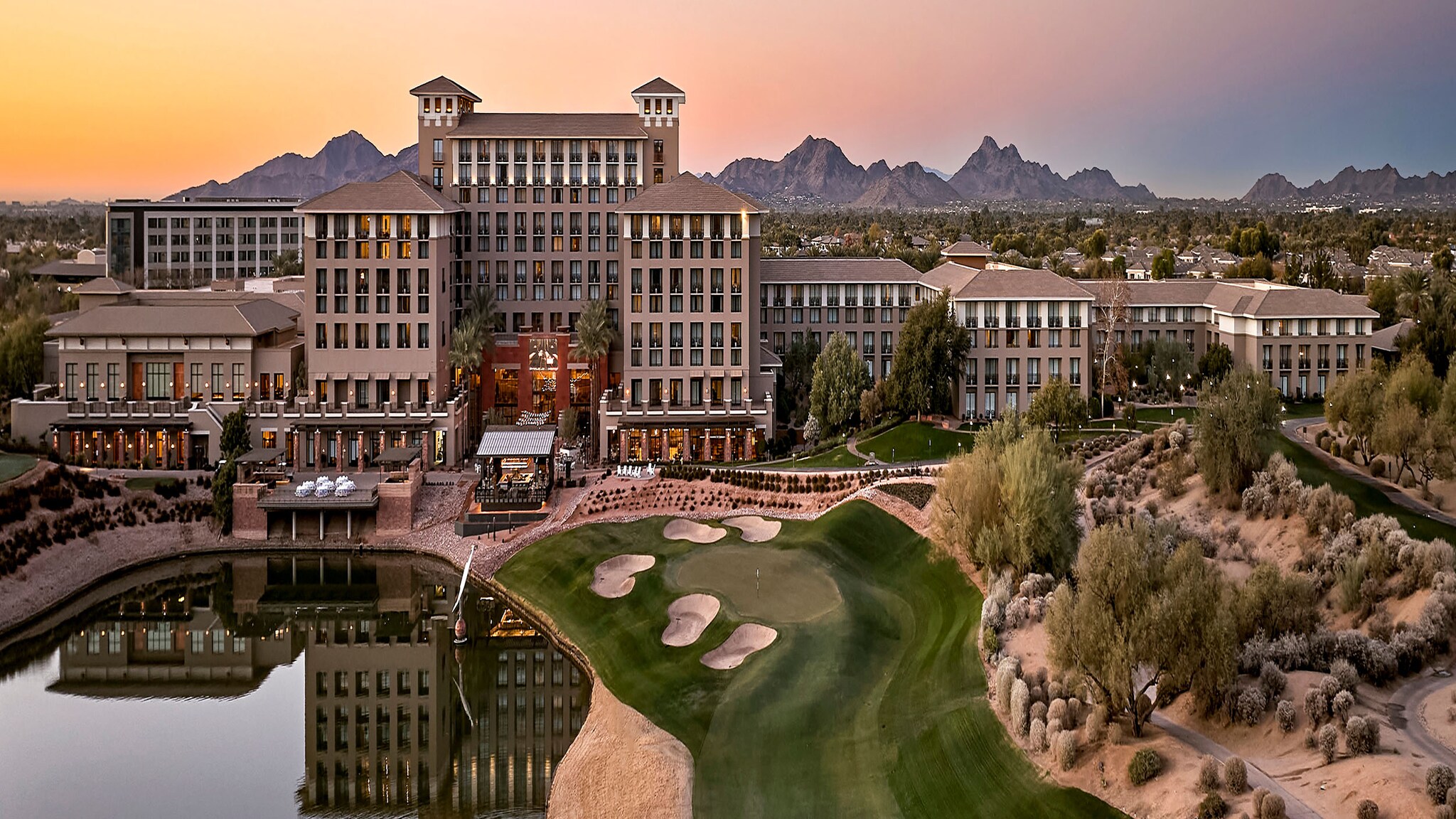 Luftaufnahme eines großen Hotels mit See und Golfplätzen.