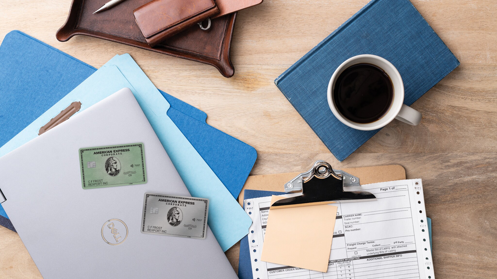 Verschiedene Arbeitsutensilien wie Laptop, Klemmbrett und Kalender liegen zusammen mit American Express Corporate Cards auf einem Tisch