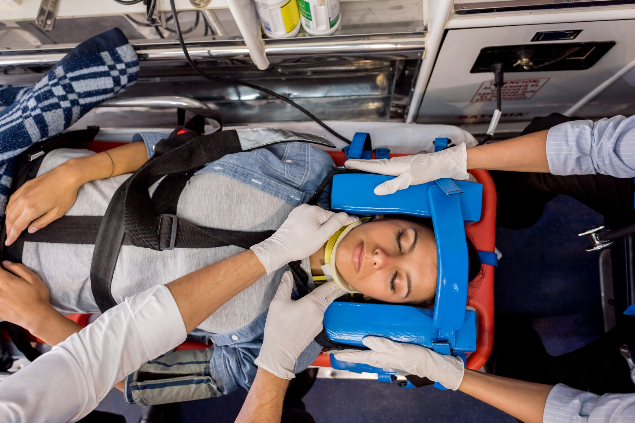 Eine Notfallpatientin liegt auf einer speziellen Liege im Krankenwagen und wird von Ärzt:innen stabilisiert.