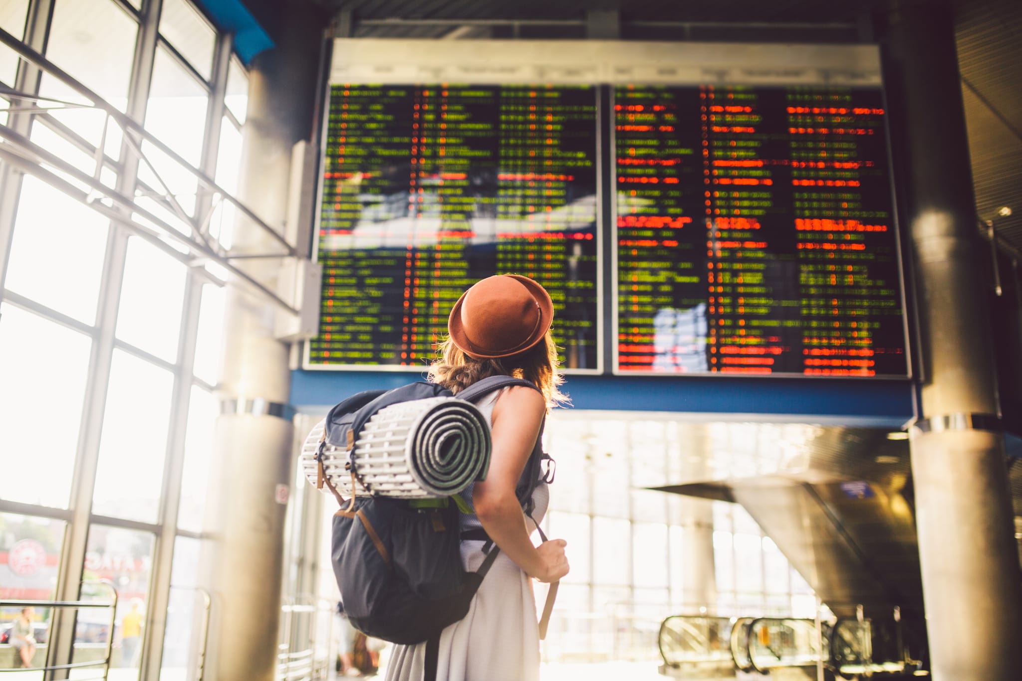 amex-insurances-kosten-bei-stornierung-einer-reise-frau-anzeigetafel Ein Paar sitzt vor einer Landkarte, plant seinen Urlaub und macht sich Notizen.