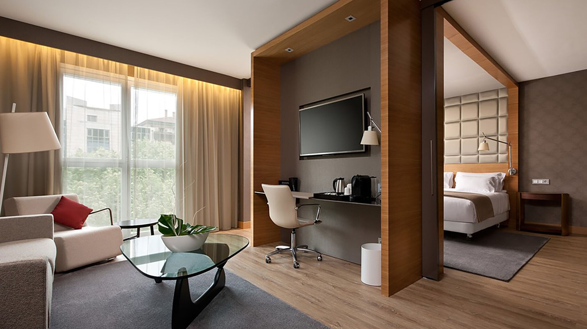 In einer Hotelsuite stehen Sofa und Tisch, im hinteren Bereich steht ein Bett.