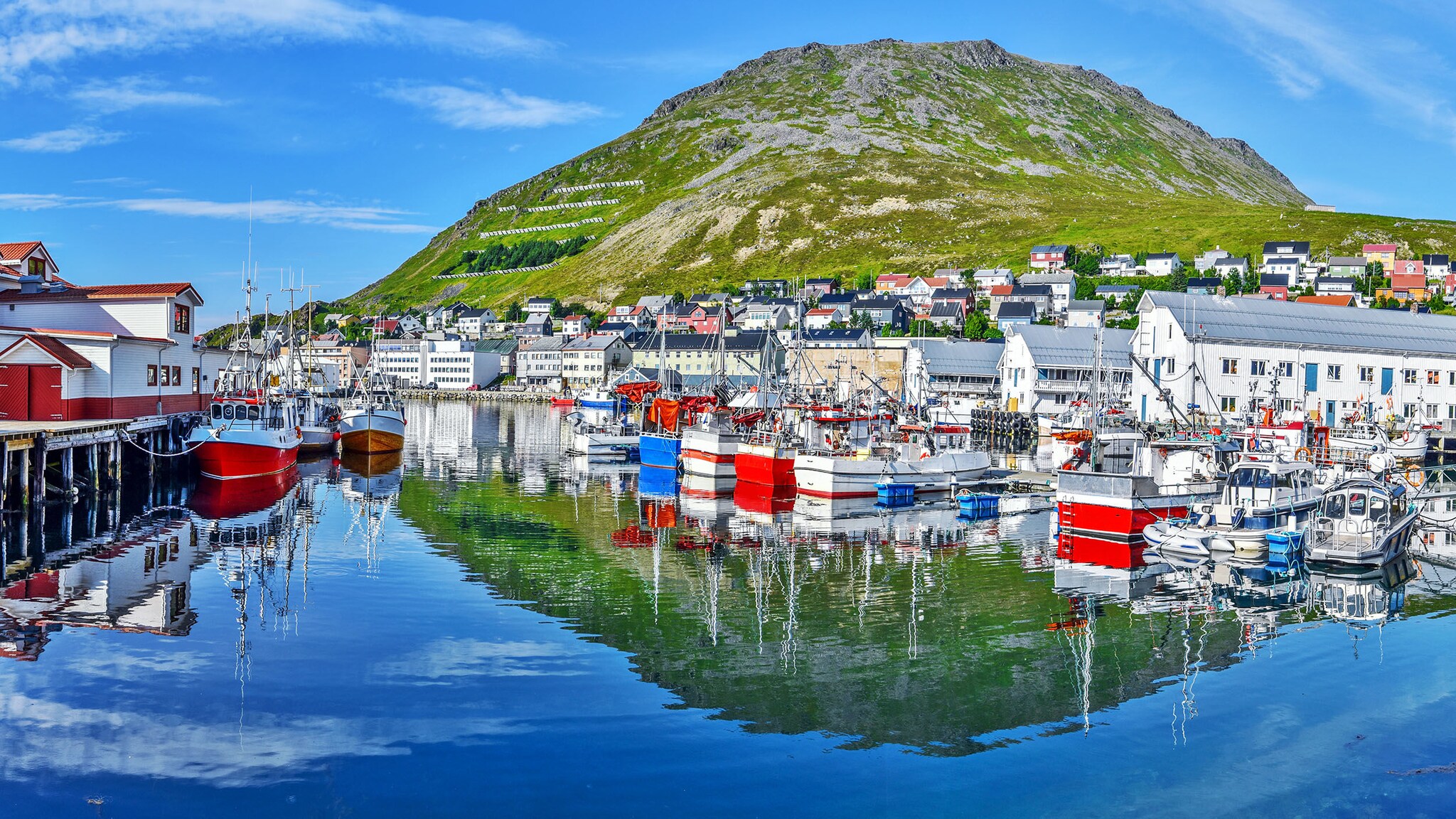 In einer Hafenstadt spiegeln sich die Häuser im Wasser.