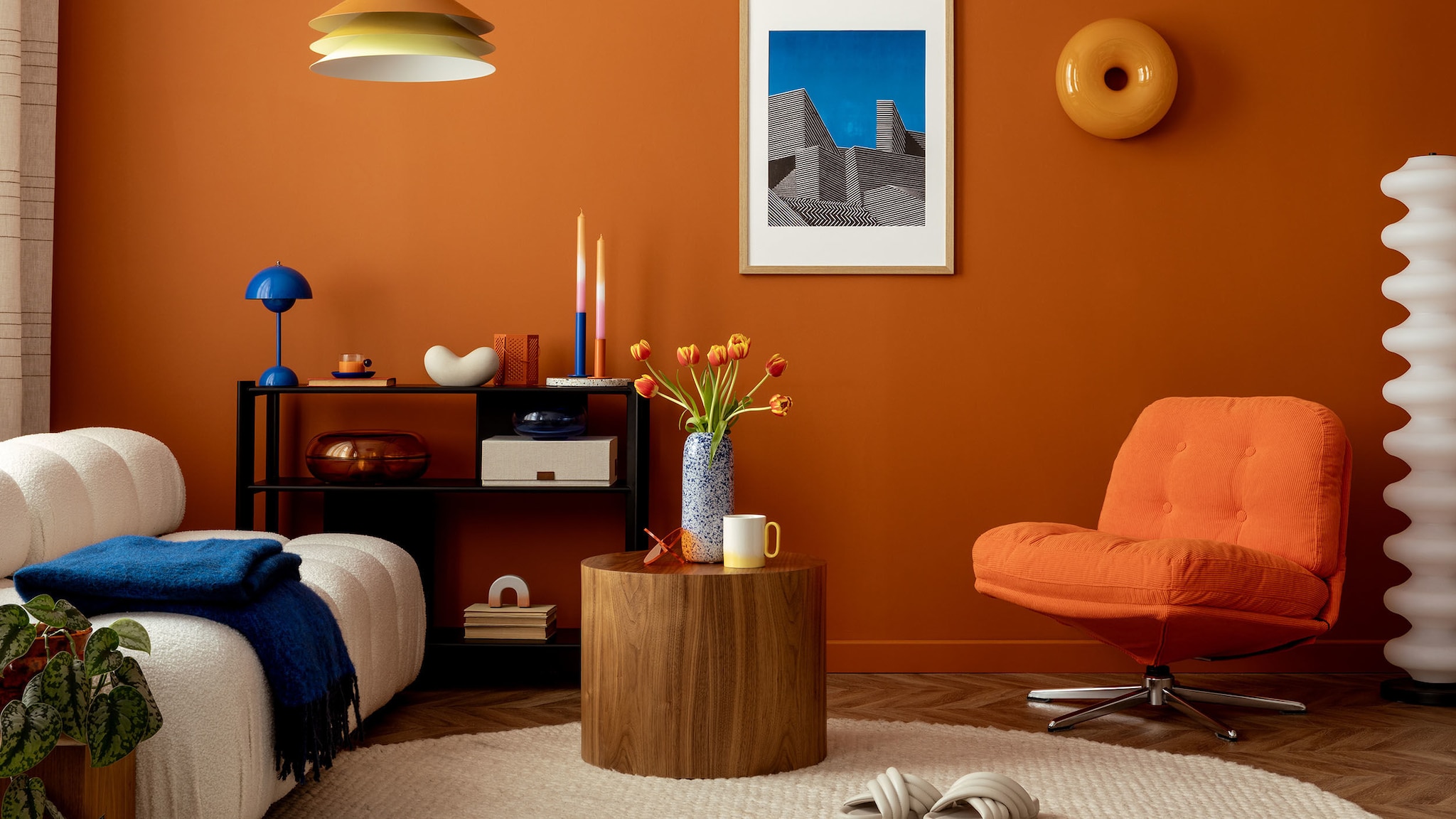 Bunte Möbel und Accessoires stehen vor einer orangefarbigen Wand. Bunte Möbel und Accessoires stehen vor einer orangefarbigen Wand.