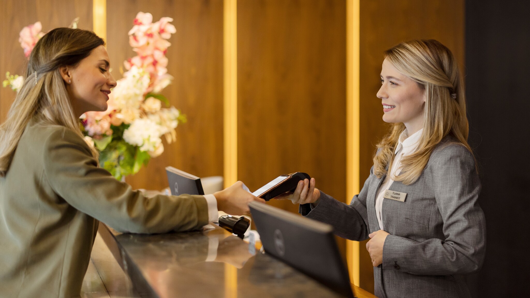 Eine Frau steht an der Rezeption eines Hotels und hält eine Karte an ein Terminal.