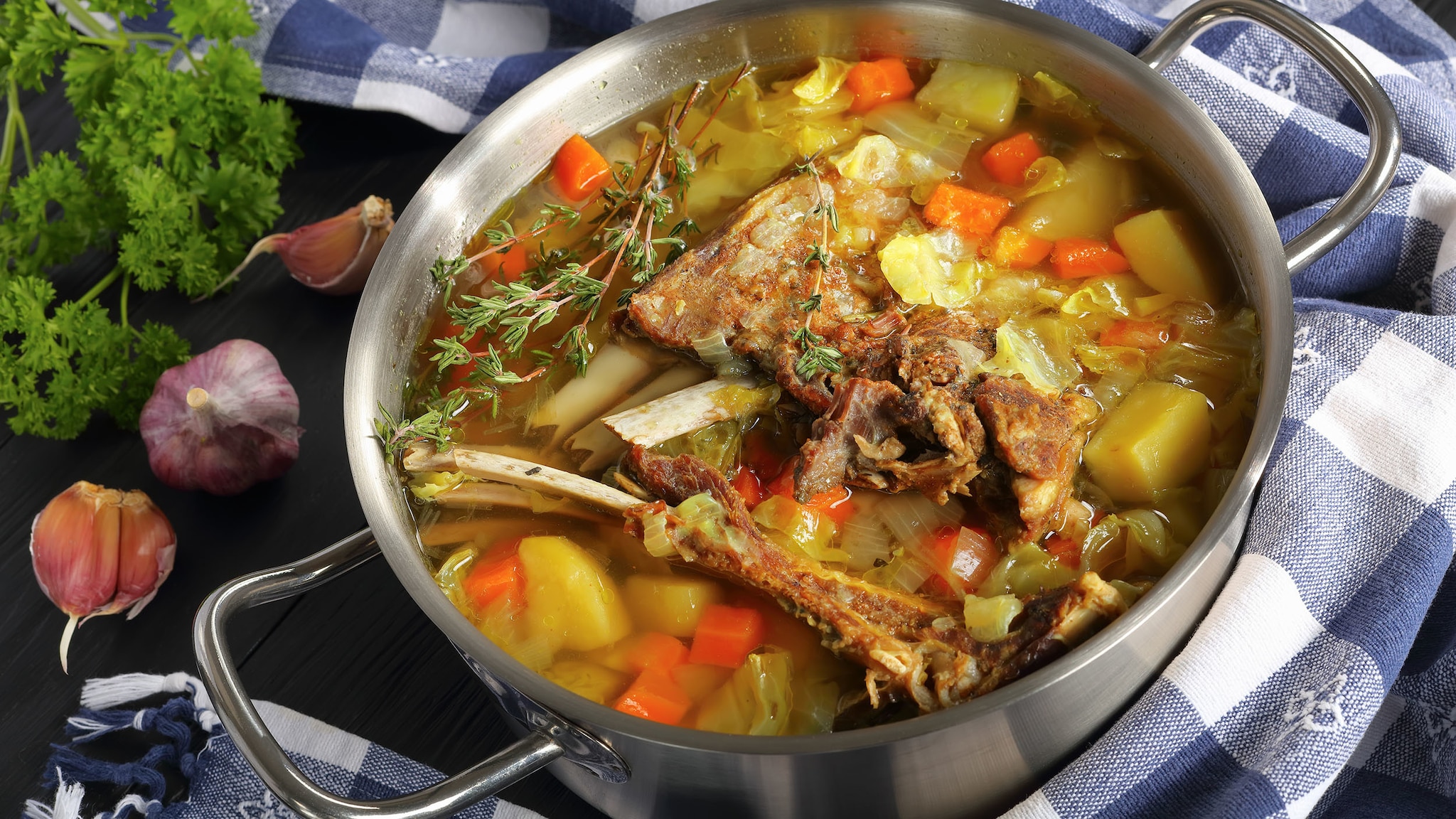 In einem Topf ist eine Suppe aus Wurzelgemüse und Fleisch.