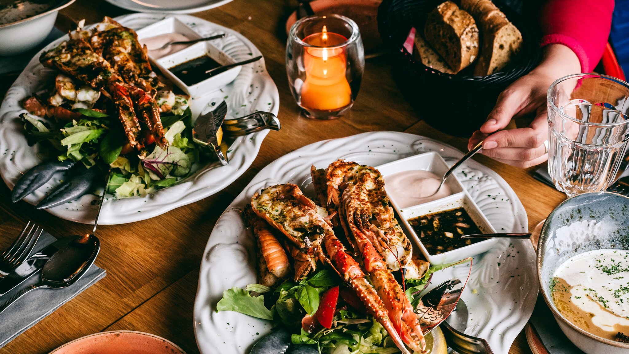 Eine Hand greift einen Löffel, der auf einem Teller mit Essen liegt.