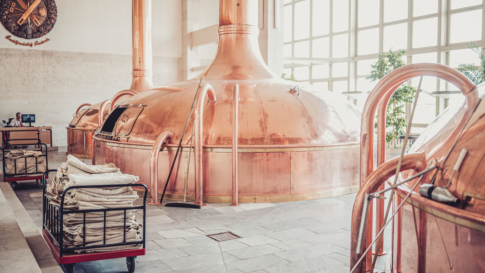 In einem hellen Raum stehen Brauereikessel aus Kupfer.