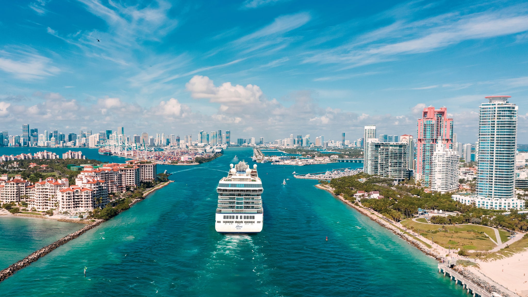 Ein Kreuzfahrtschiff fährt durch eine Bucht, an den Seiten stehen Häuser.