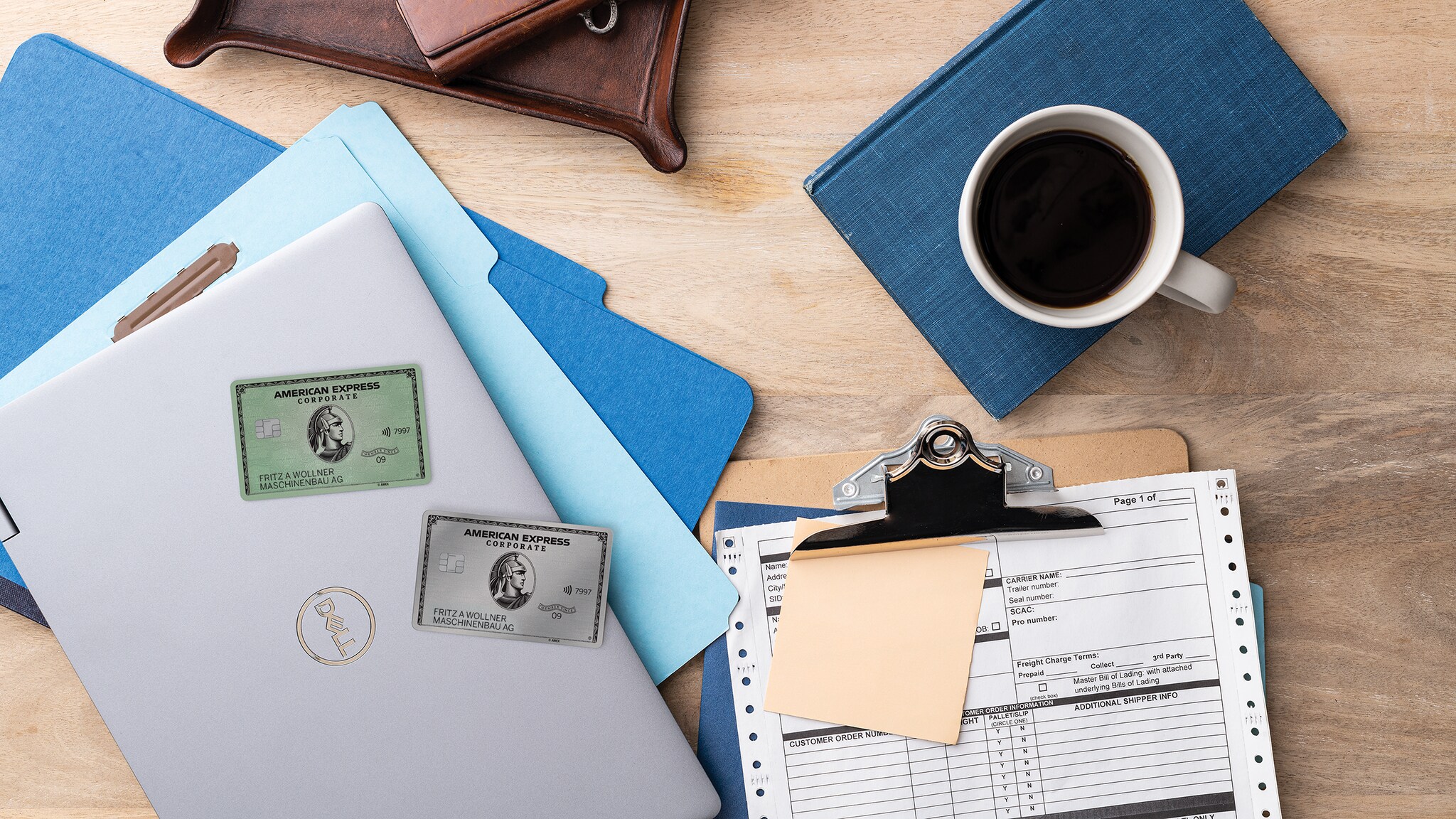 Verschiedene Arbeitsutensilien wie Laptop, Klemmbrett und Kalender liegen zusammen mit American Express Corporate Cards auf einem Tisch