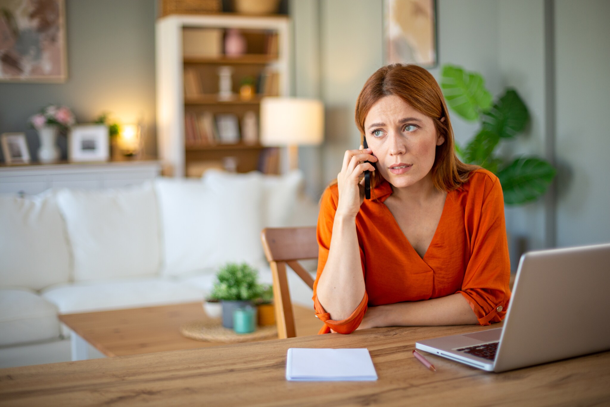 Eine Frau telefoniert, vor ihr ein Computer sowie Zettel und Stift.