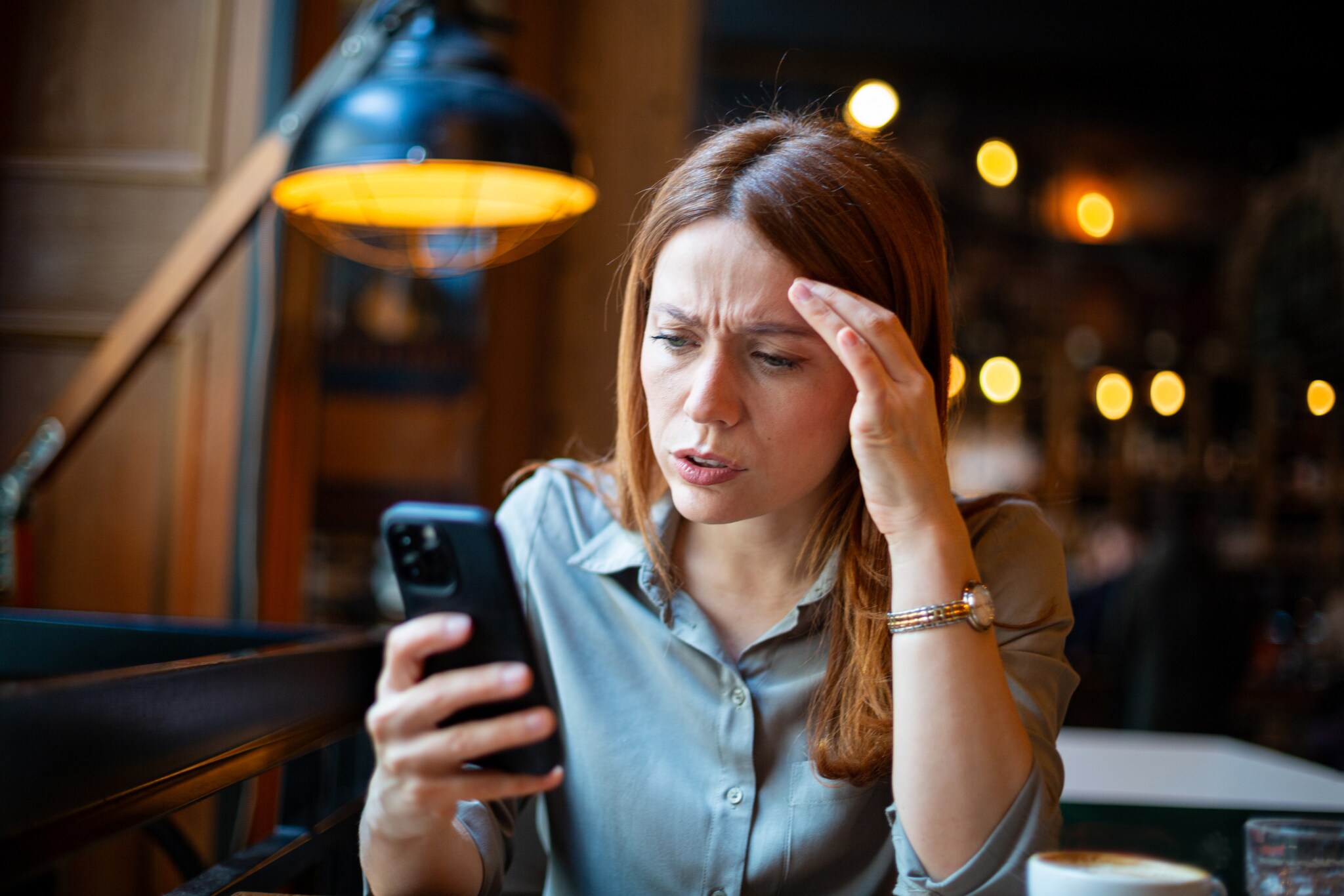 Eine Frau schaut verärgert auf ihr Handy.