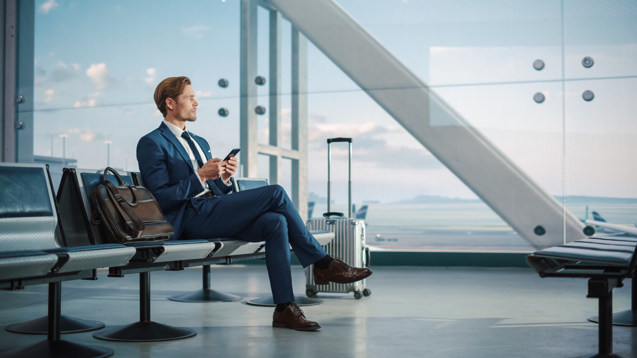 Ein Geschäftsmann wartet in einer Abflughalle in einem Flughafen.