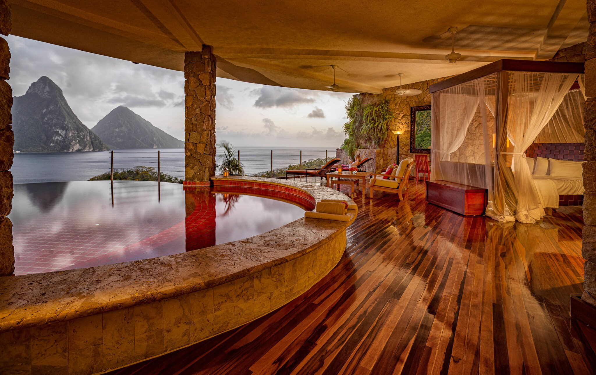 Offene Luxussuite im Jade Mountain Resort auf St. Lucia mit Himmelbett, Holzboden und privatem Infinity-Pool. Im Hintergrund sind die Pitons und das Karibische Meer zu sehen.