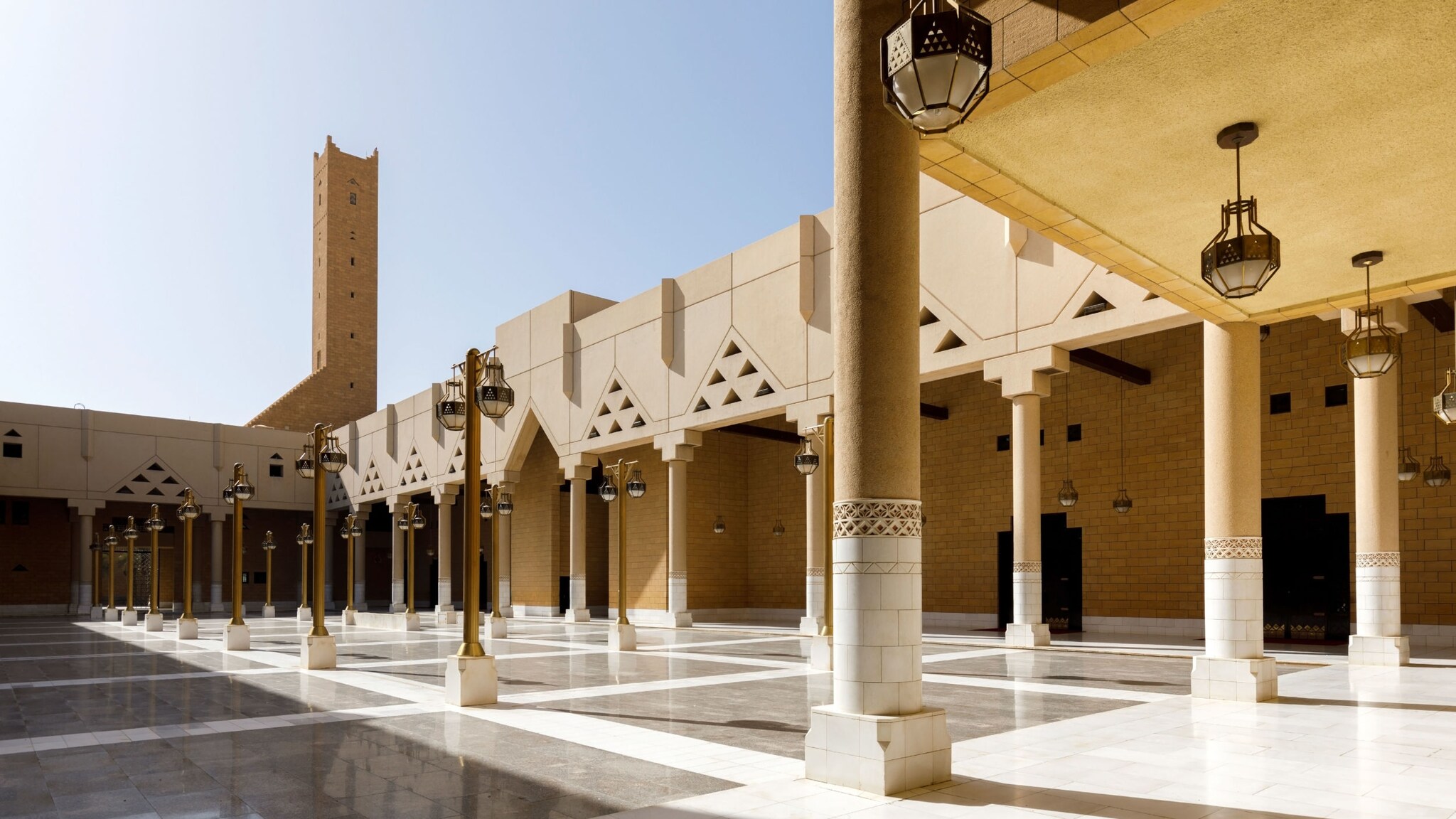 Menschenleerer Innenhof einer Moschee mit Säulengang bei Sonnenschein. 