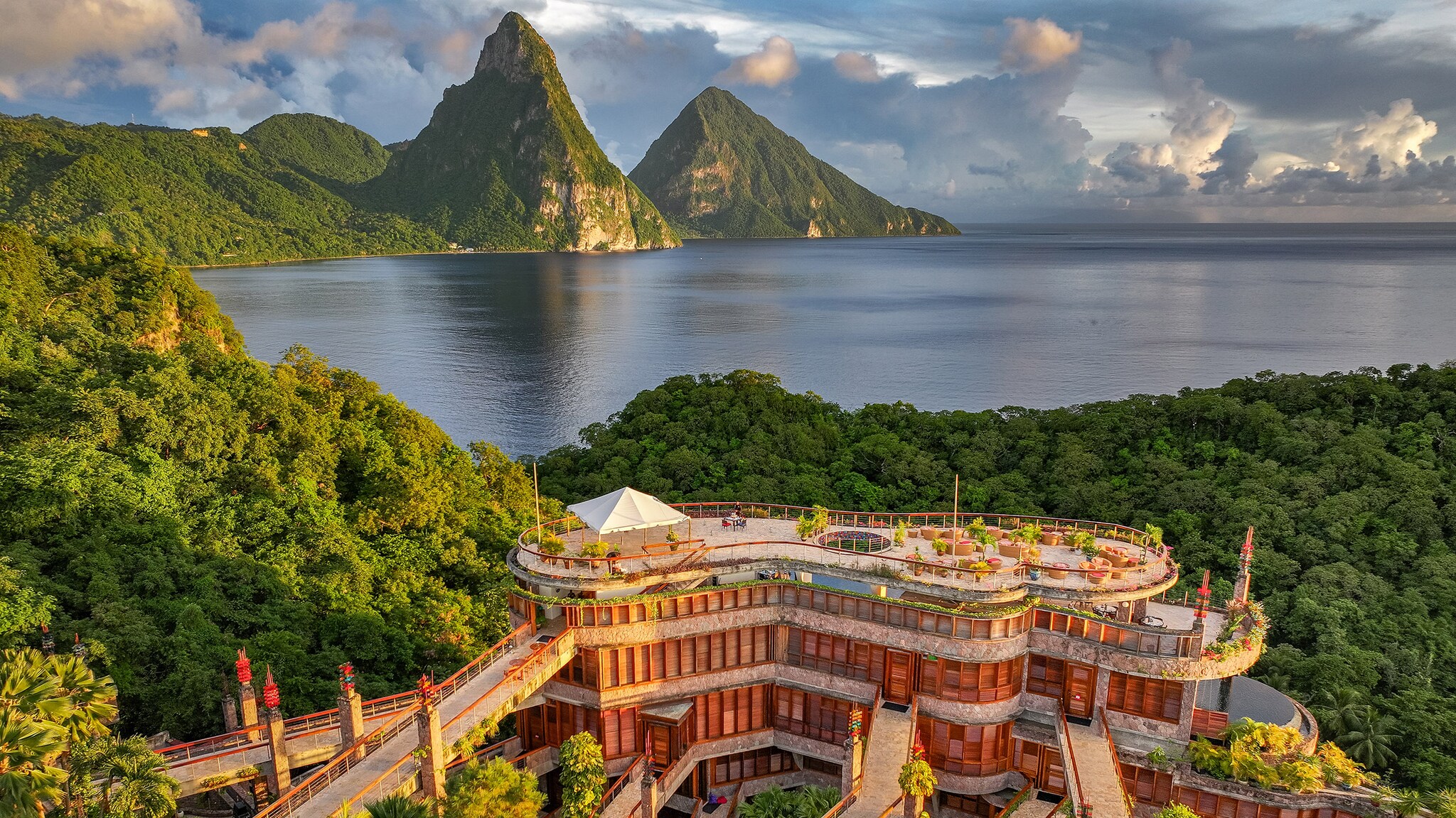 Blick von oben auf das Jade Mountain Resort im tropischen Regenwald von St. Lucia. Im Hintergrund ragen die beiden grünen Pitons über dem Karibischen Meer auf.