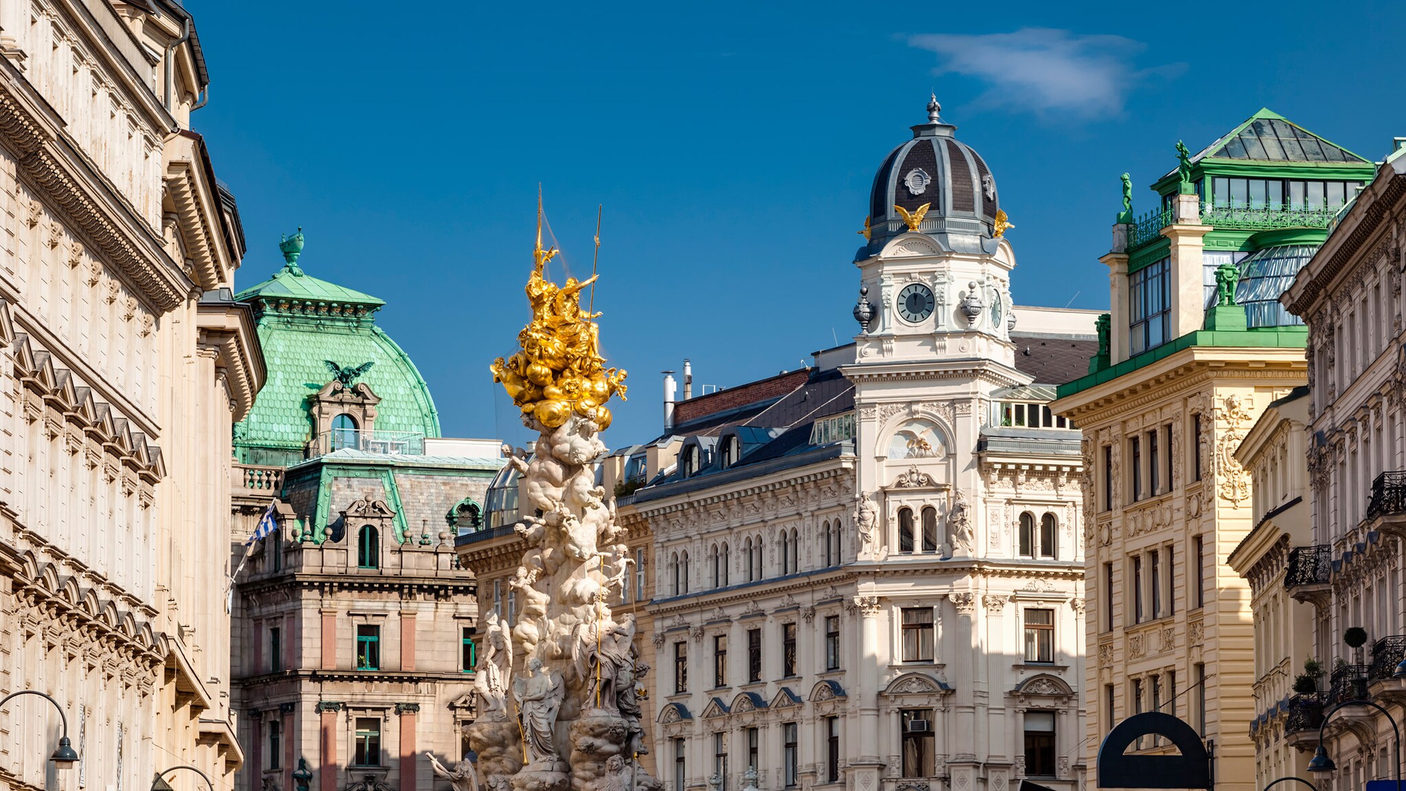 Monumentale Prachtbauten mit vergoldeter Säule in der Wiener Innenstadt unter blauem Himmel.