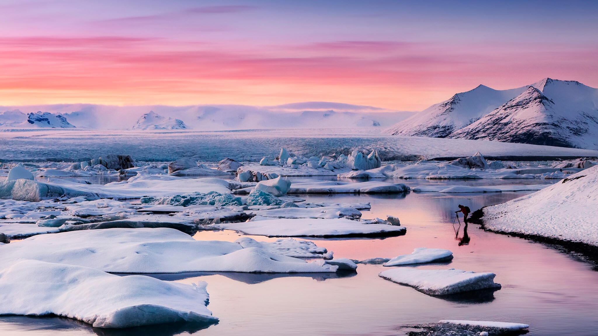 Die einsame Gletscherlagune Jökulsárlón bei malerischem Sonnenuntergang vor einem rosa leuchtendem Himmel. 