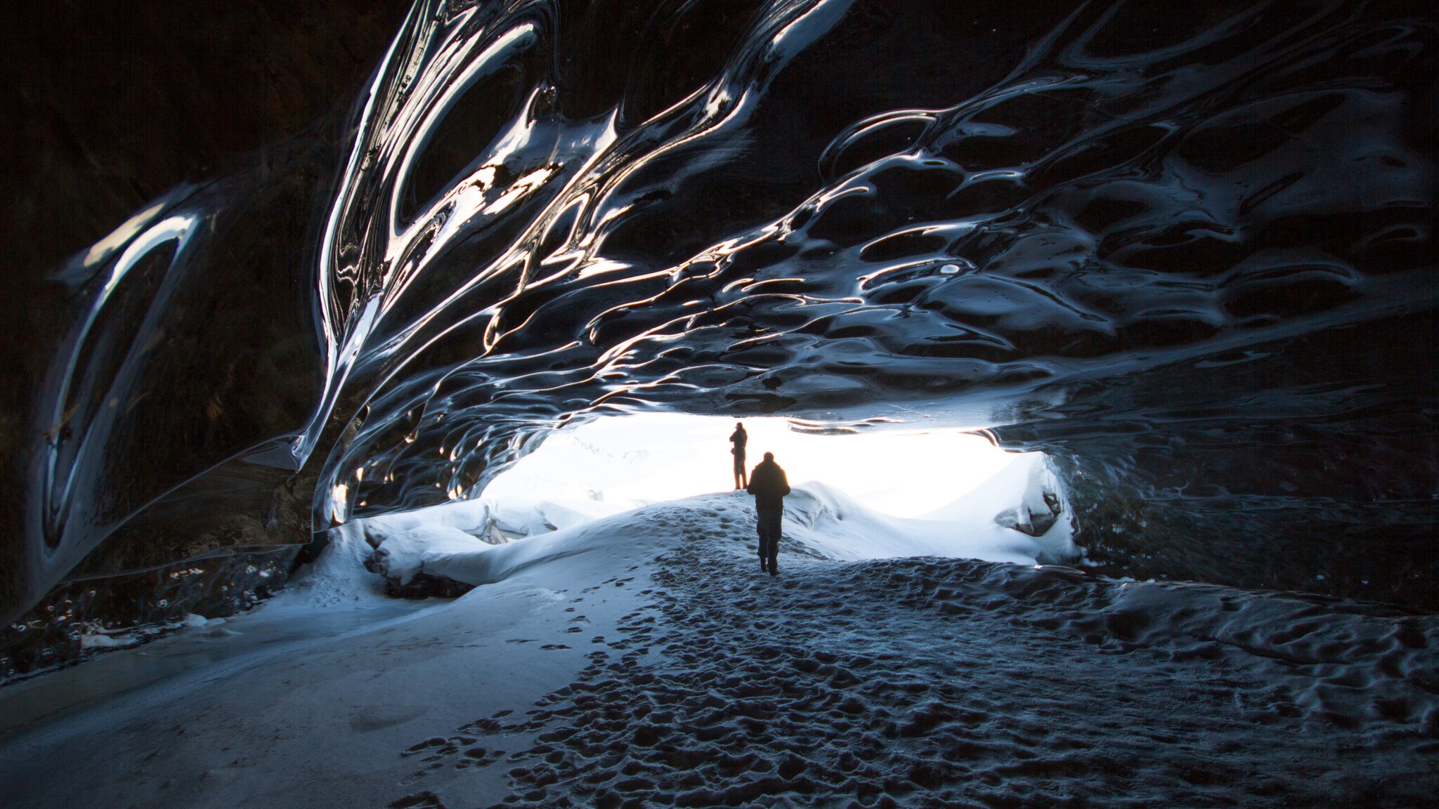 Zwei Männer stehen am Eingang einer Eishöhle im Langjökull-Gletscher auf Island.