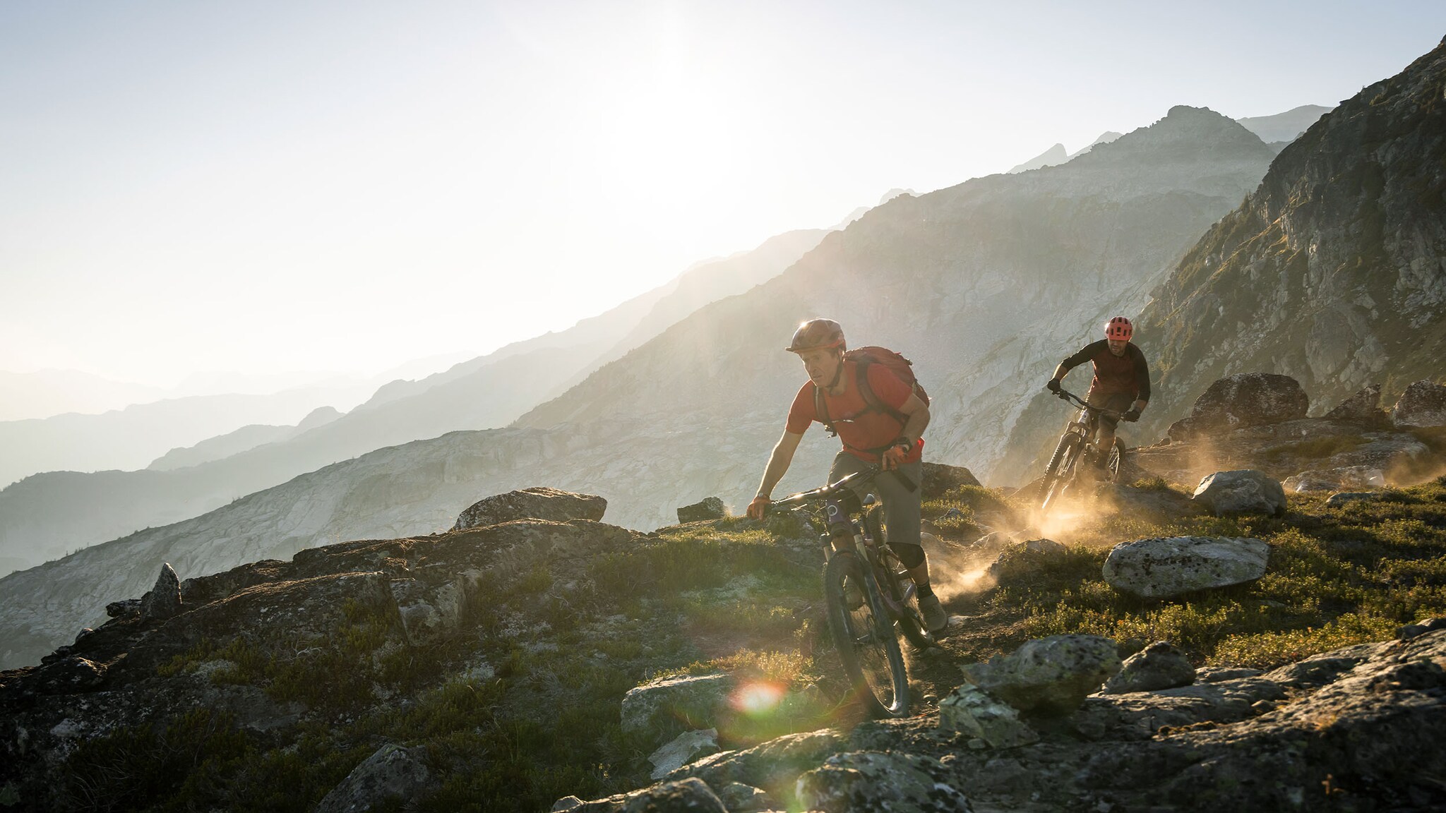 Zwei Personen fahren auf ihren Mountainbikes durch eine bergige Landschaft.
