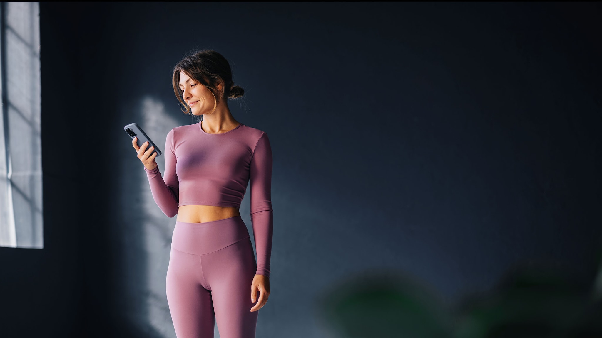 Eine Frau in Yoga-Kleidung schaut auf ihr Smartphone.