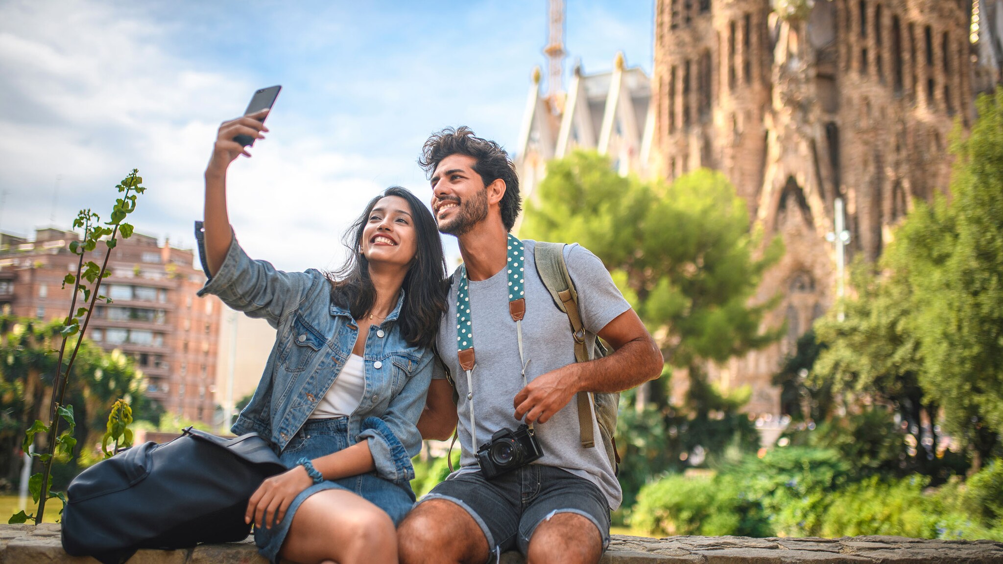 Eine Frau und ein Mann sitzen vor einem historischen Gebäude und machen ein Selfie.l
