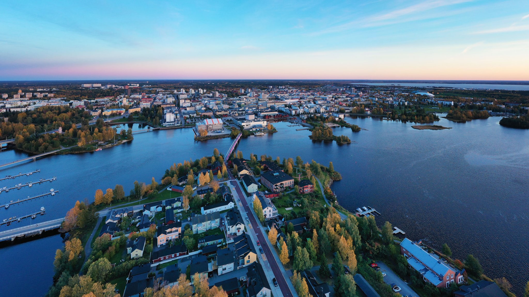 Luftaufnahme einer nordischen Stadt an einem Flussdelta in bläulichem Licht bei Abenddämmerung.