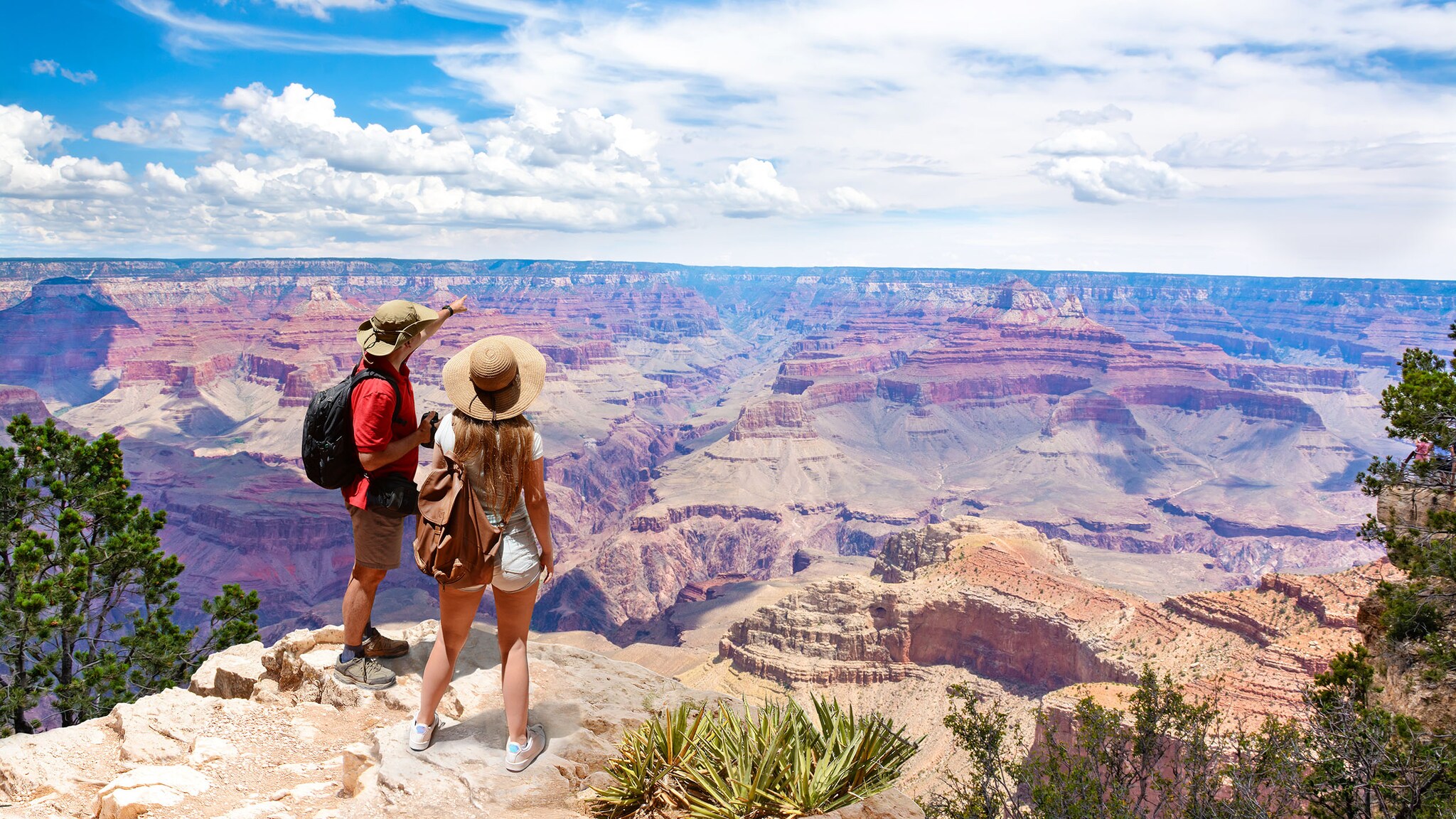 Eine Frau und ein Mann stehen vor dem Grand Canyon und blicke in die Landschaft.