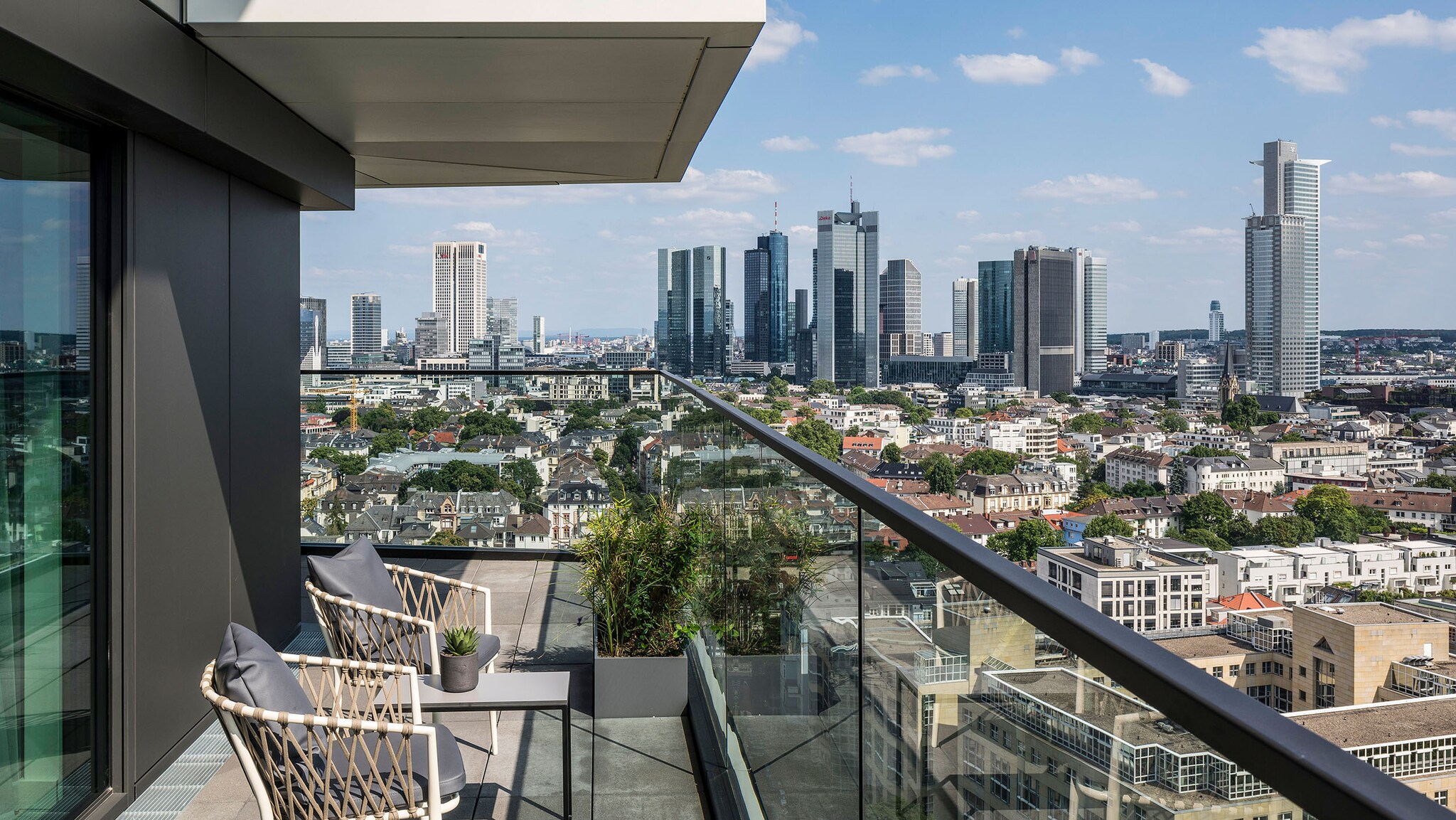 Hinter der Terrasse eines Hotels ragt die Skyline von Frankfurt empor.