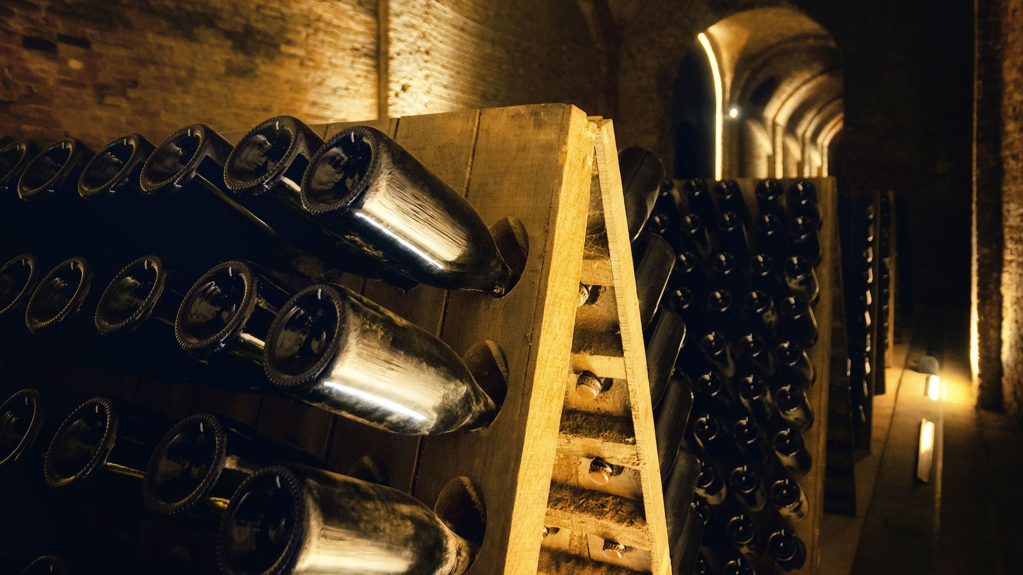 Sektflaschen, die kopfüber während der Flaschengärung auf Rüttelbrettern gelagert werden, in einem Keller.
