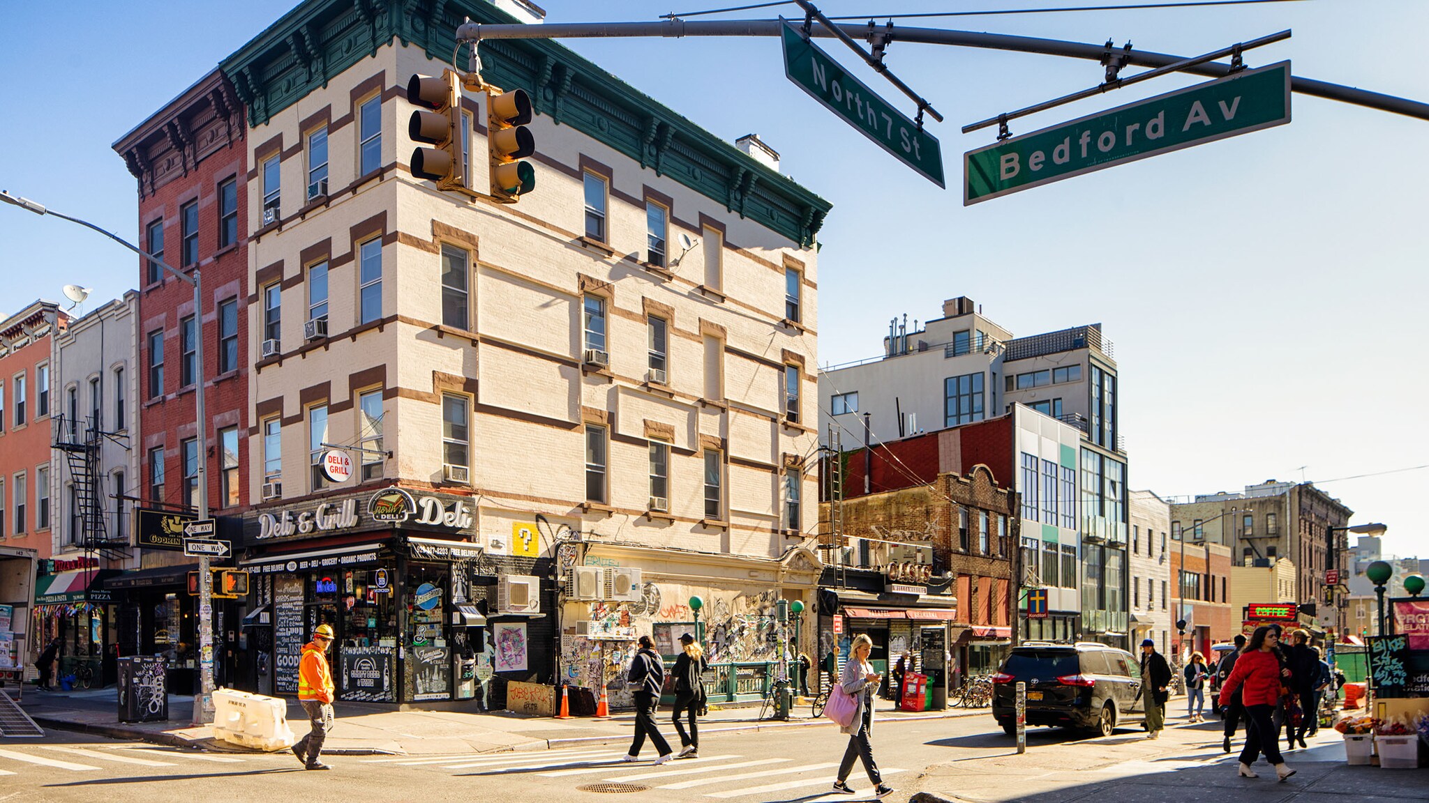 Menschen an einer Straßenecke mit unterschiedlichen Häusern und grünen US-amerikanischen Straßenschildern.
