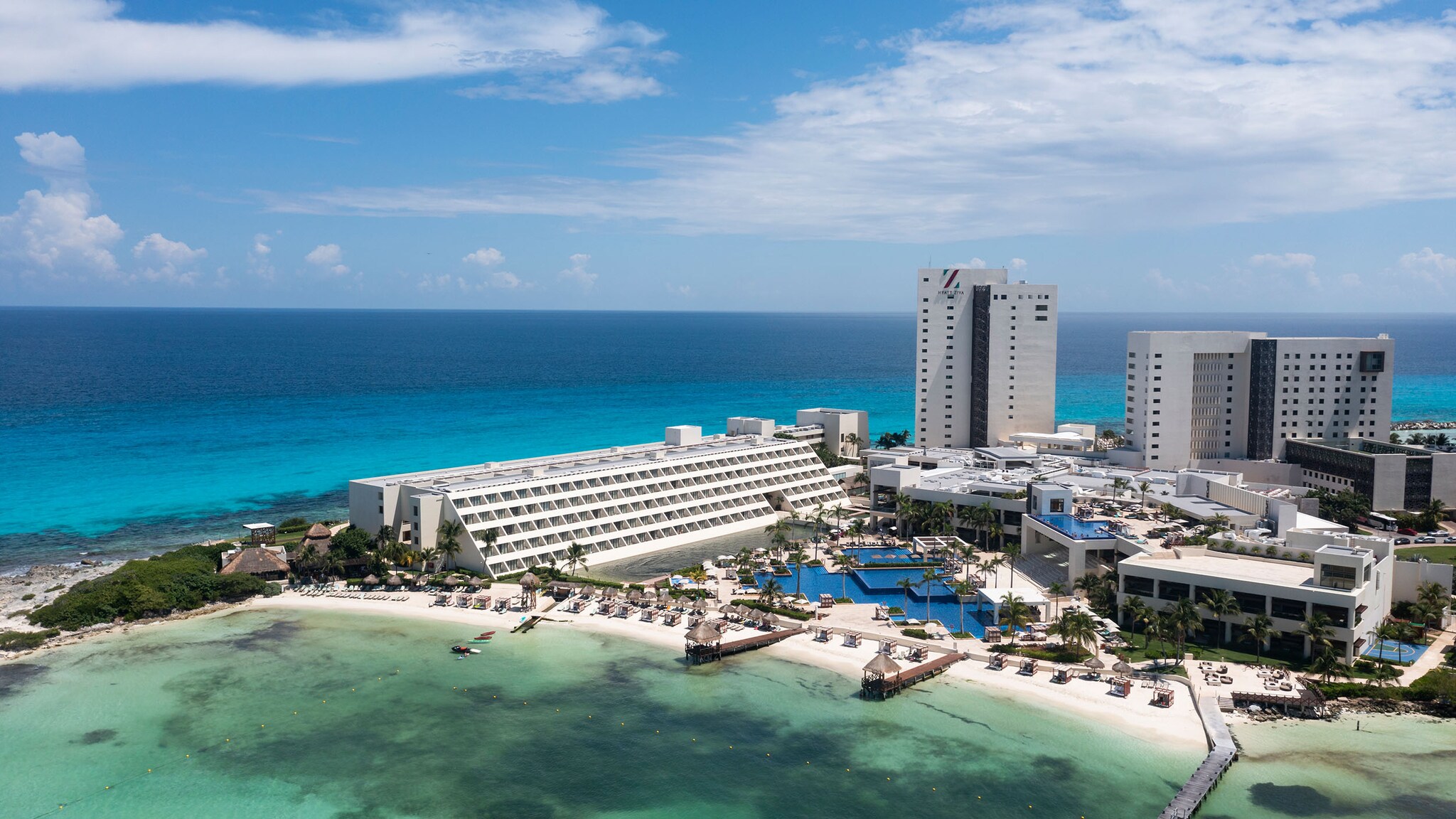 An einer Küste direkt am Meer liegt ein Hotel-Resort mit futuristischem Gebäude.