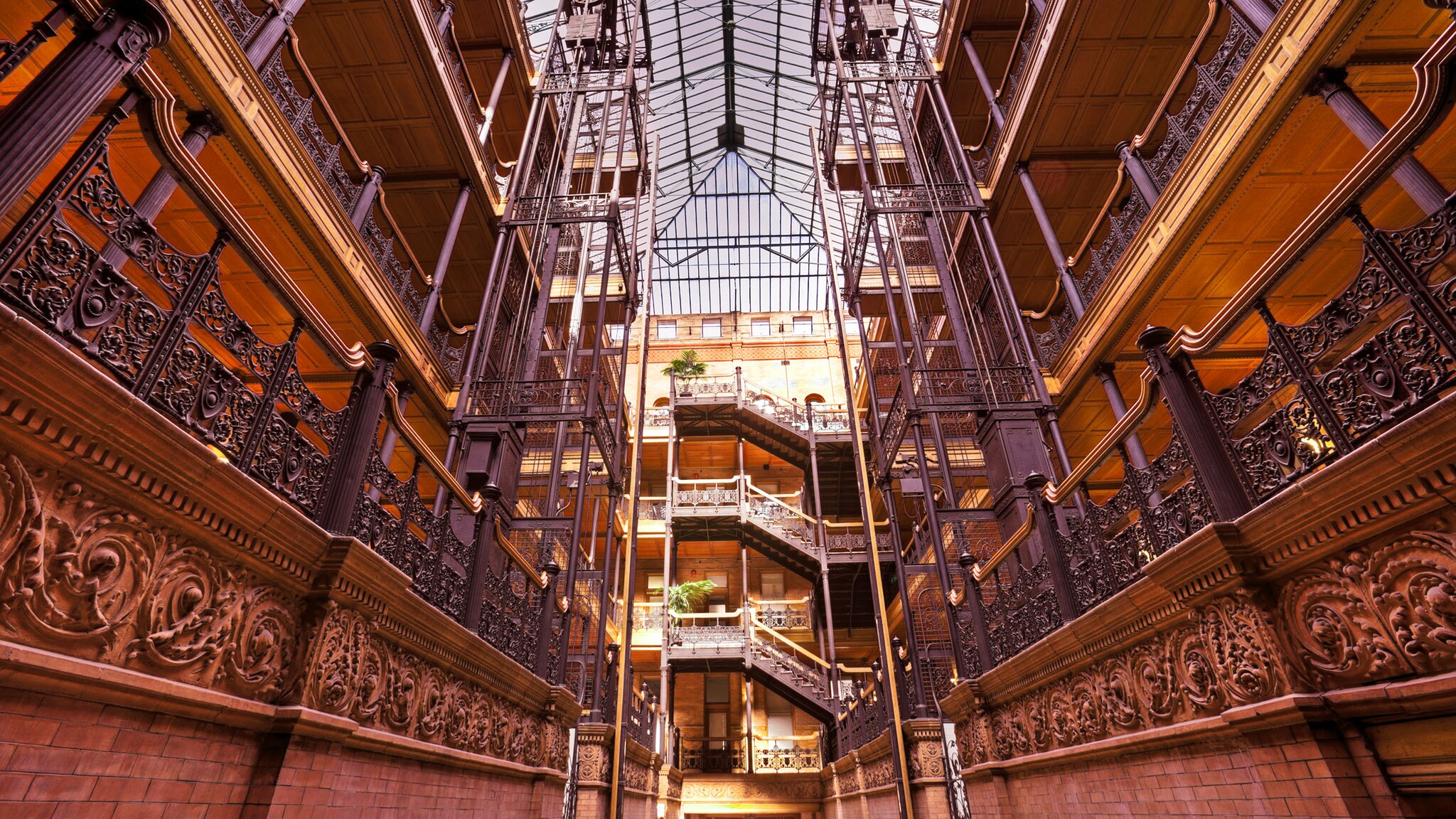 Viktorianisches Innenatrium mit kunstvollen Marmortreppen und Schmiedeeisen-Verzierungen in einem historischen Gebäude unter einem großen Glasdach.