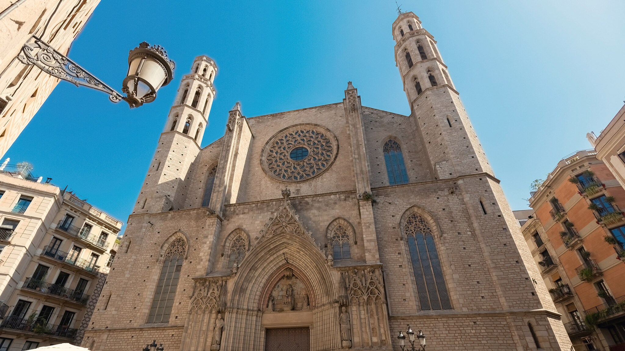 Fassade mit Eingangsbereich einer gotischen Kirche unter blauem Himmel.