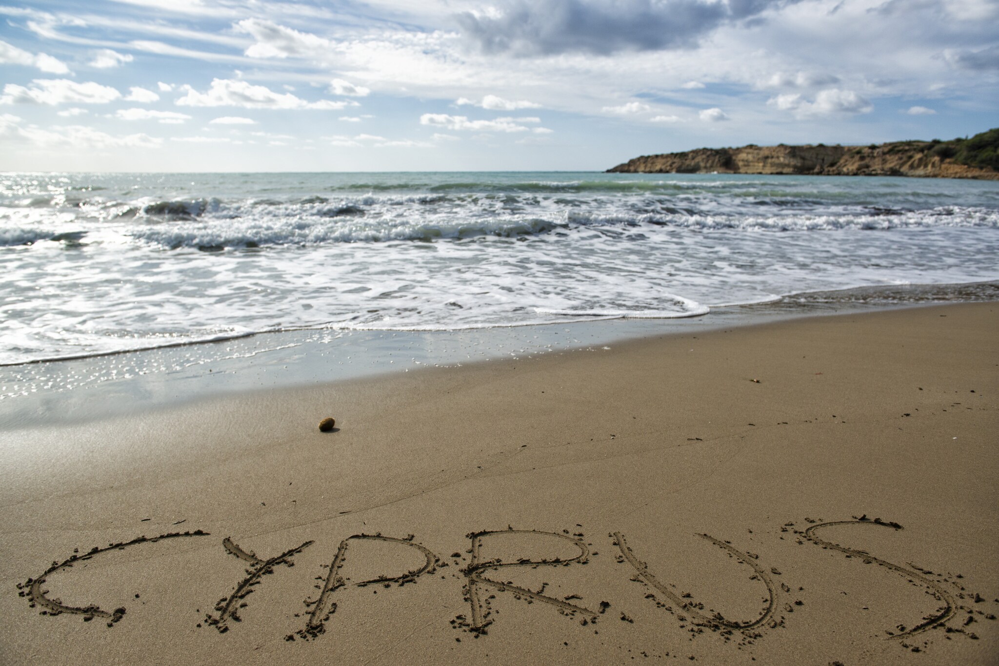 Schriftzug Cyprus im Sand am welligen Meer auf Zypern.
