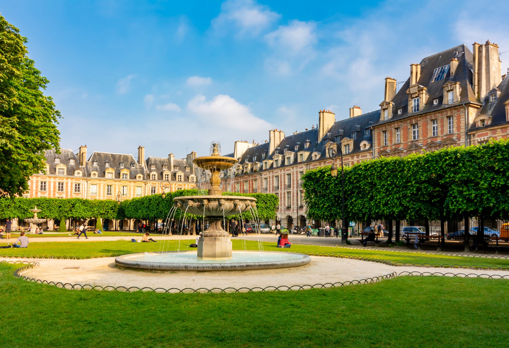 Blick auf die grüne Place des Vosges mit Springbrunnen in der Mitte.