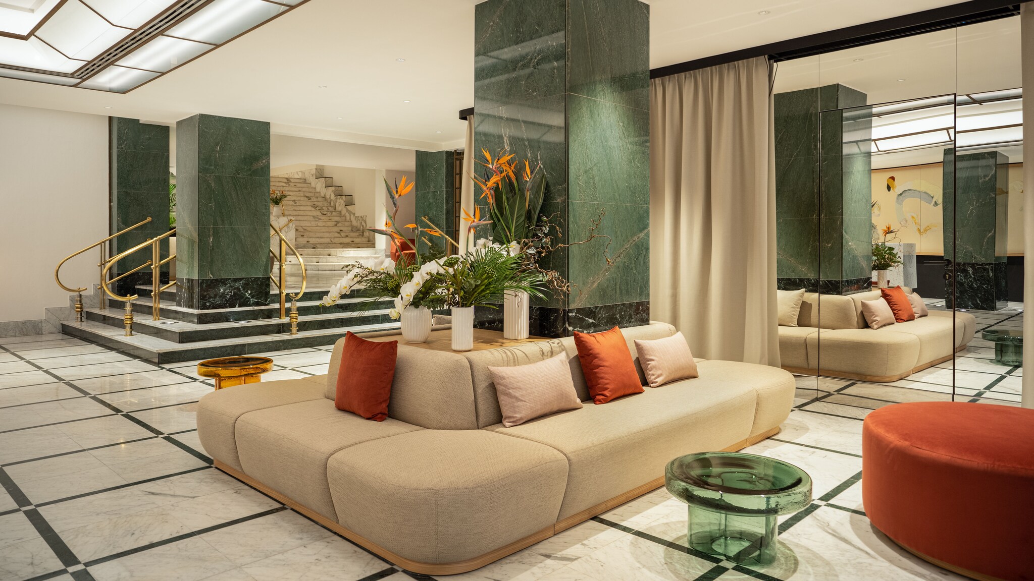 Moderne Lobby mit geschwungener Couch und Design-Möbeln vor einer Spiegelwand.