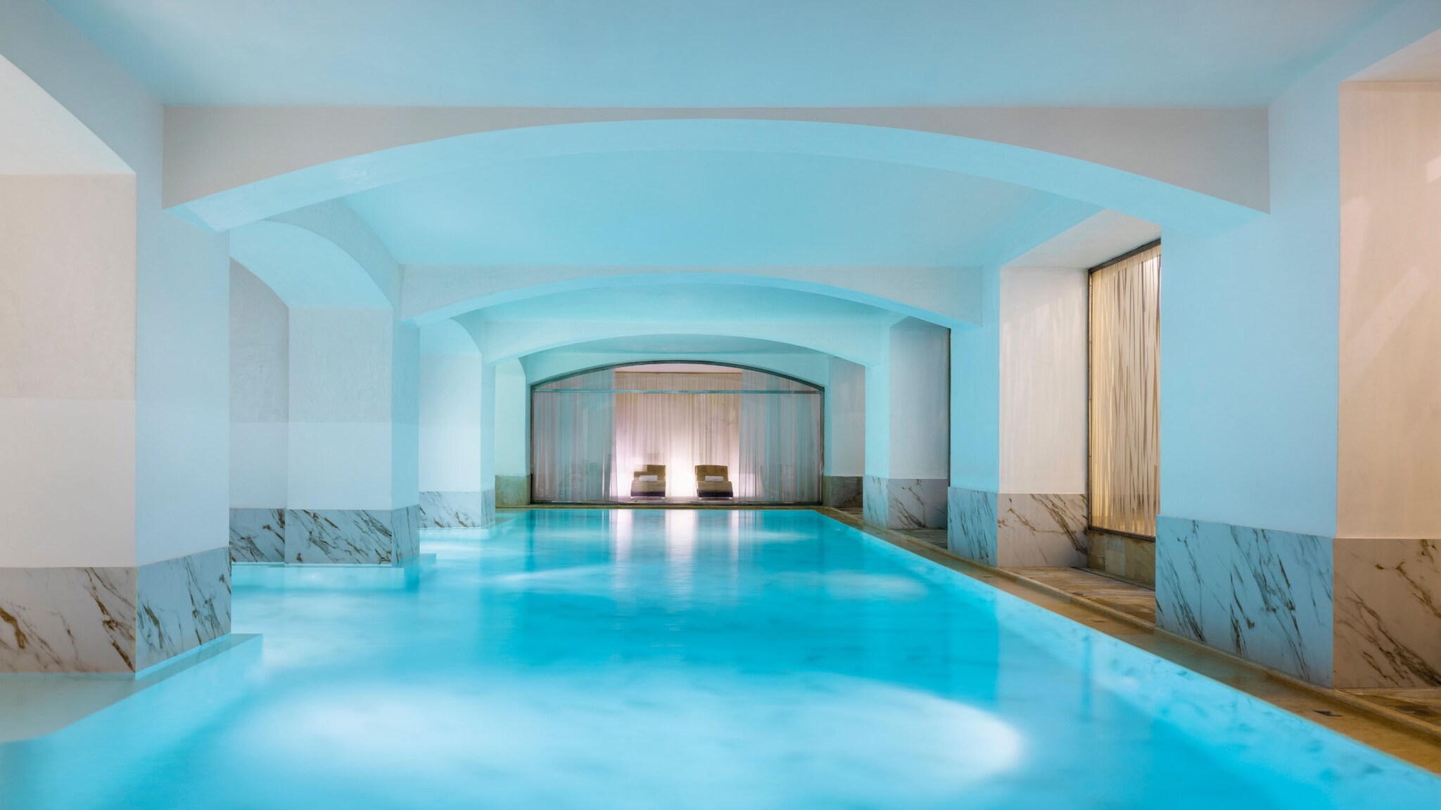 Luxuriöser Spabereich mit beleuchtetem Indoorpool und Liegen.