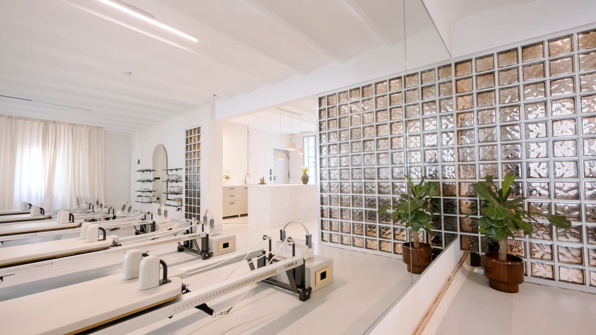 In einem weißen Raum mit Fensterglas stehen Pilates-Reformer.