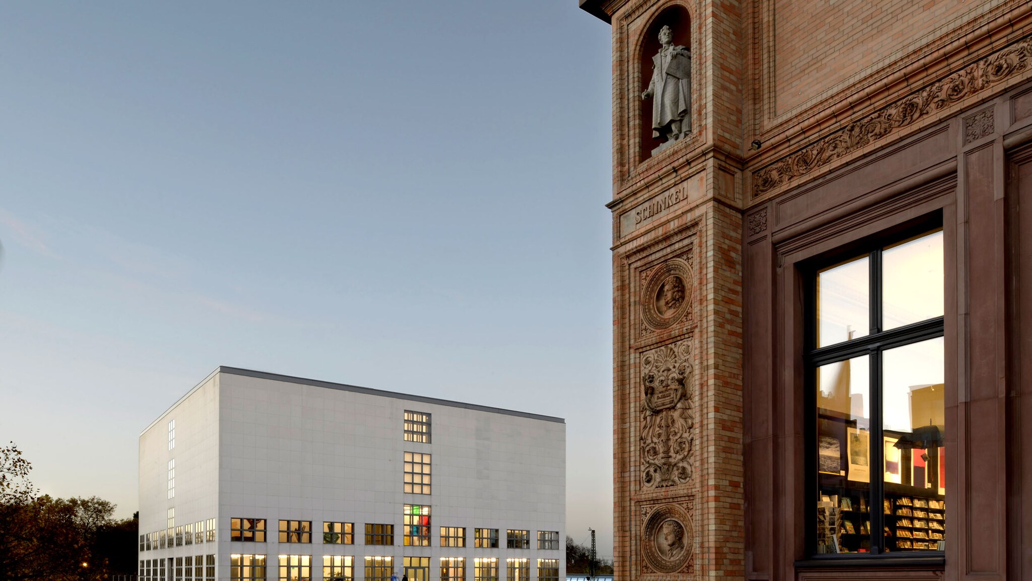 Ausschnitt eines historischen Gebäudes mit Fenster, im Hintergrund ragt ein Neubau empor. 