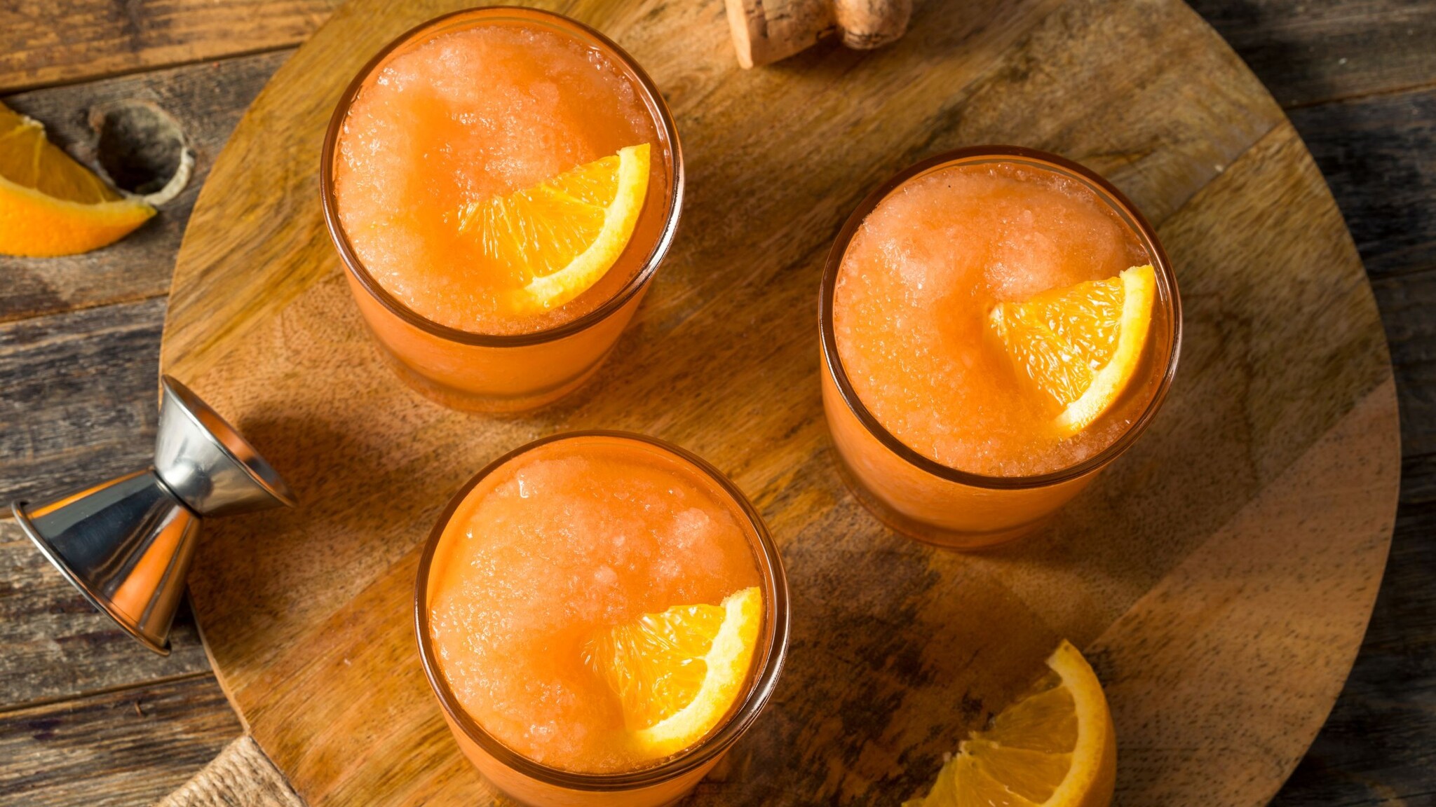 Aufsicht auf Gläser mit einem orangefarbenen gefrorenen Getränk mit Orangenscheiben. 